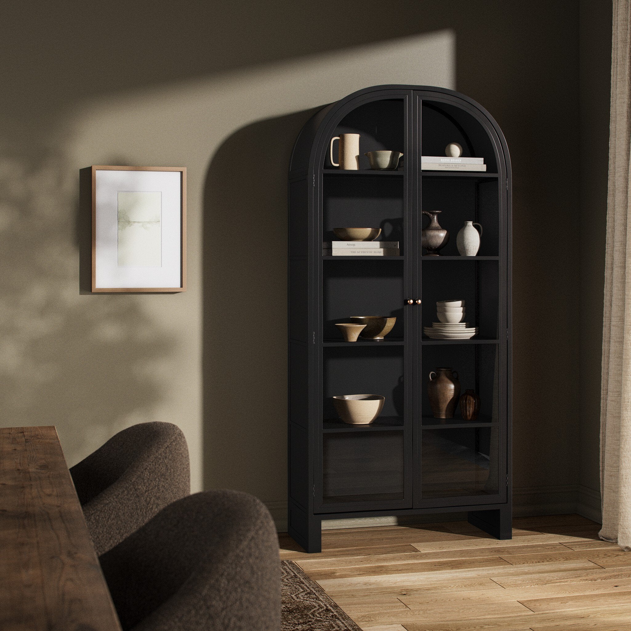 Dark wooden bookshelf with decorative items in a room with a sofa and framed picture.