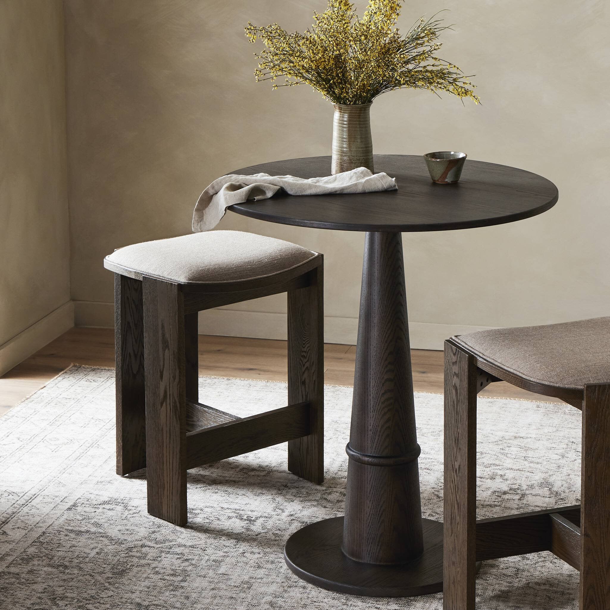 Round wooden table with two stools in a room setting