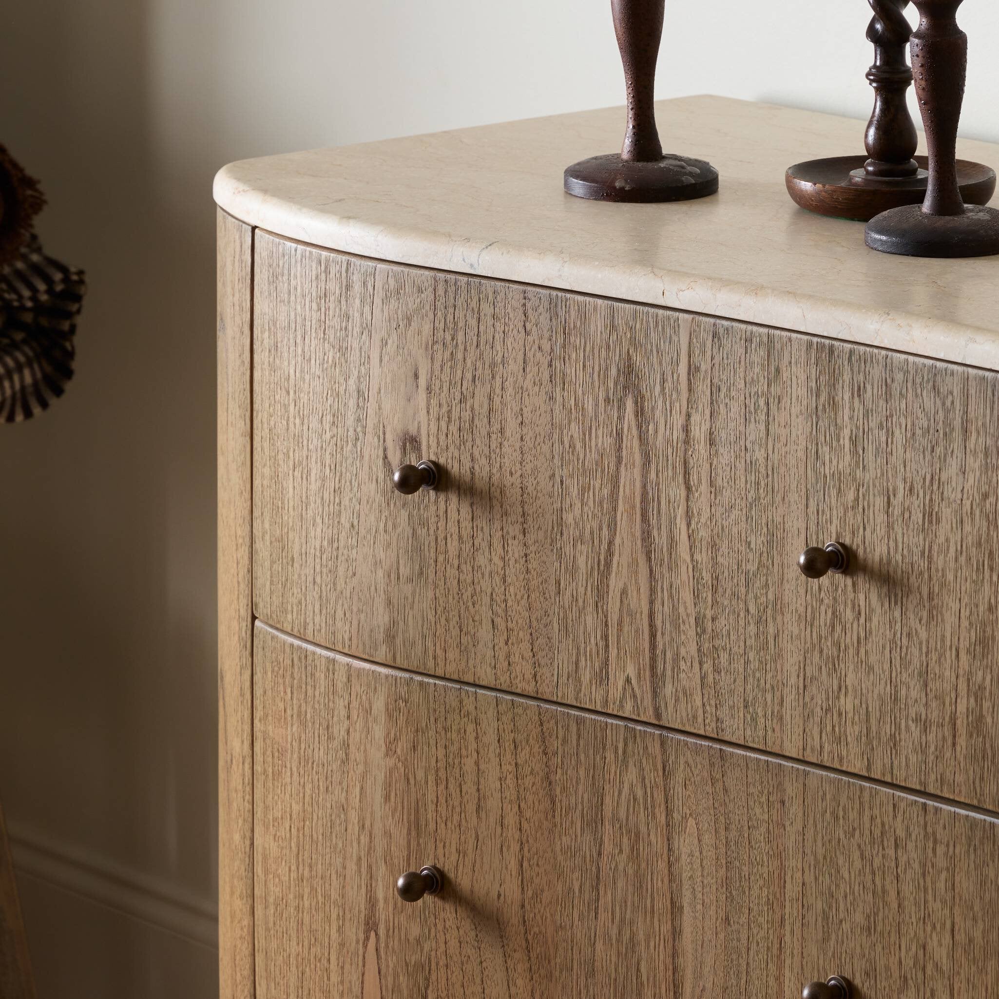 Wooden dresser with marble top and decorative items on a neutral background