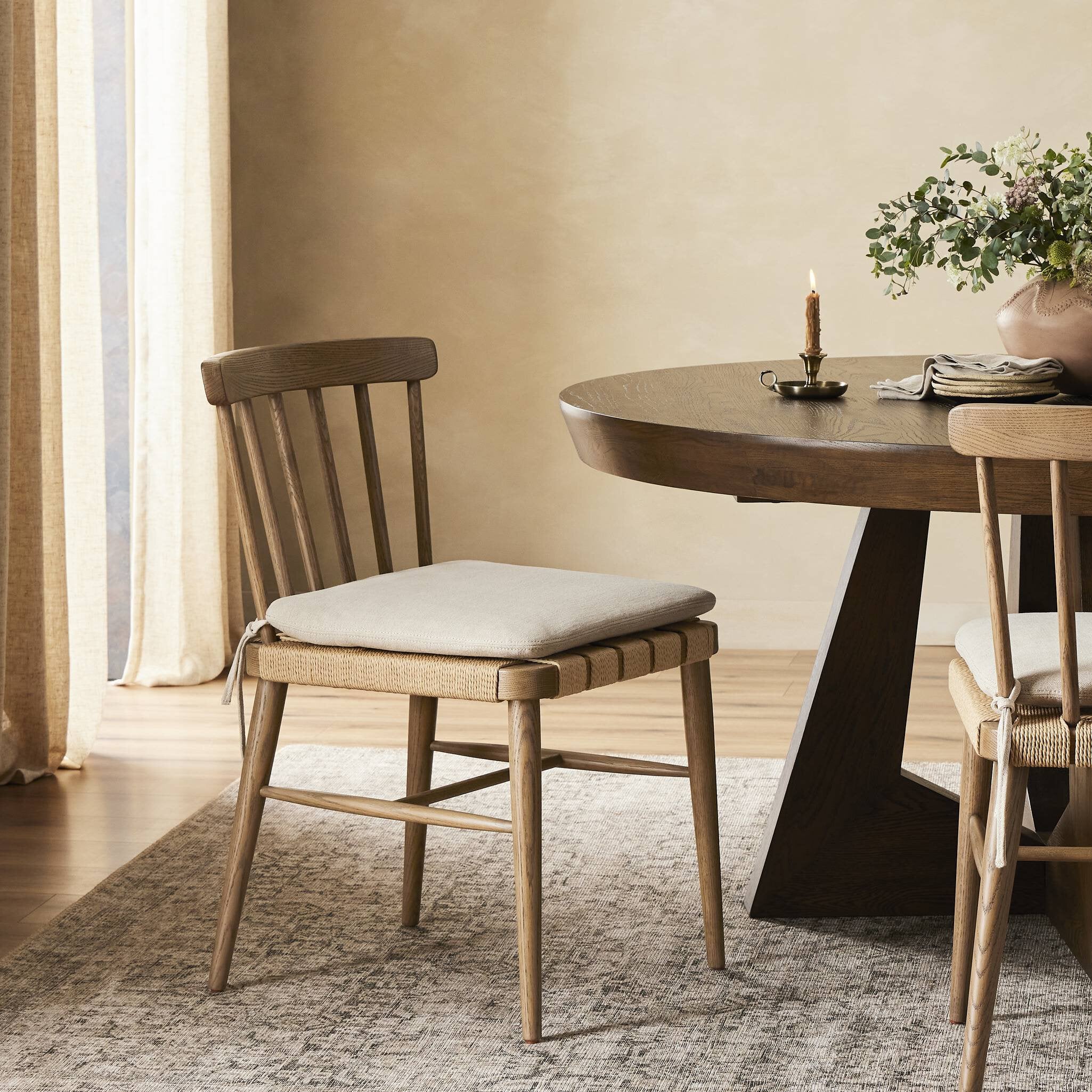 Dining room with wooden table and chairs, featuring a candle and decorative items.