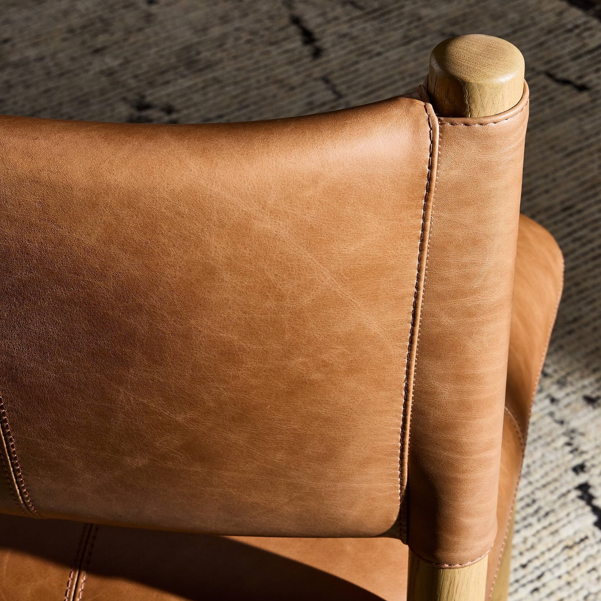 Close up of a brown leather dining chair with wooden frame on a white background.