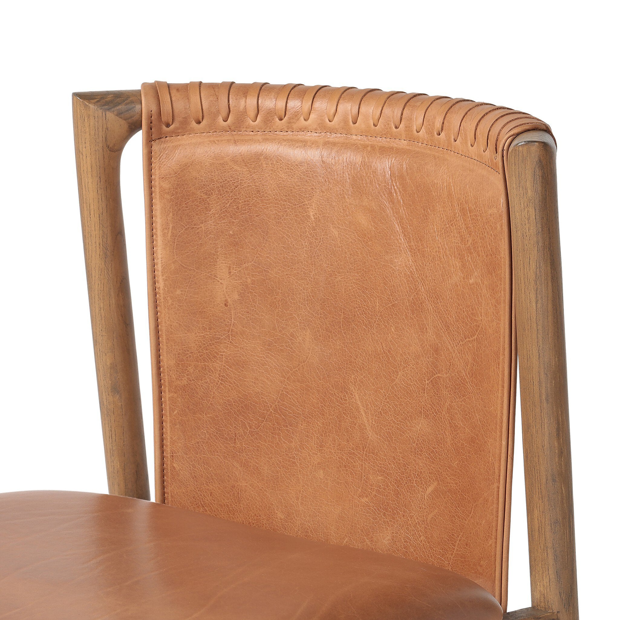 Close up of a tobacco-grain leather chair with leather wrap detailing on a wooden frame on a white background.