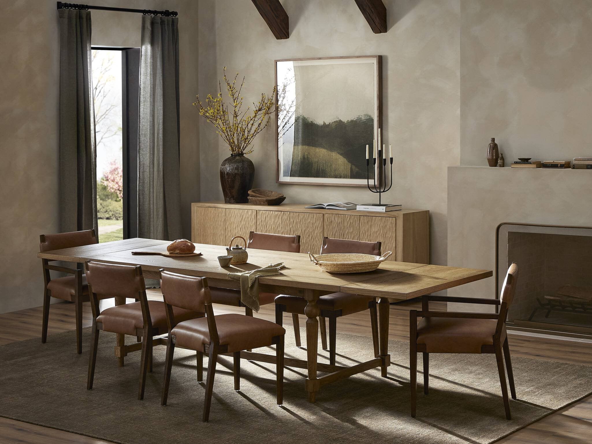 Dining room with wooden table and chairs, large mirror on the wall, and fireplace.