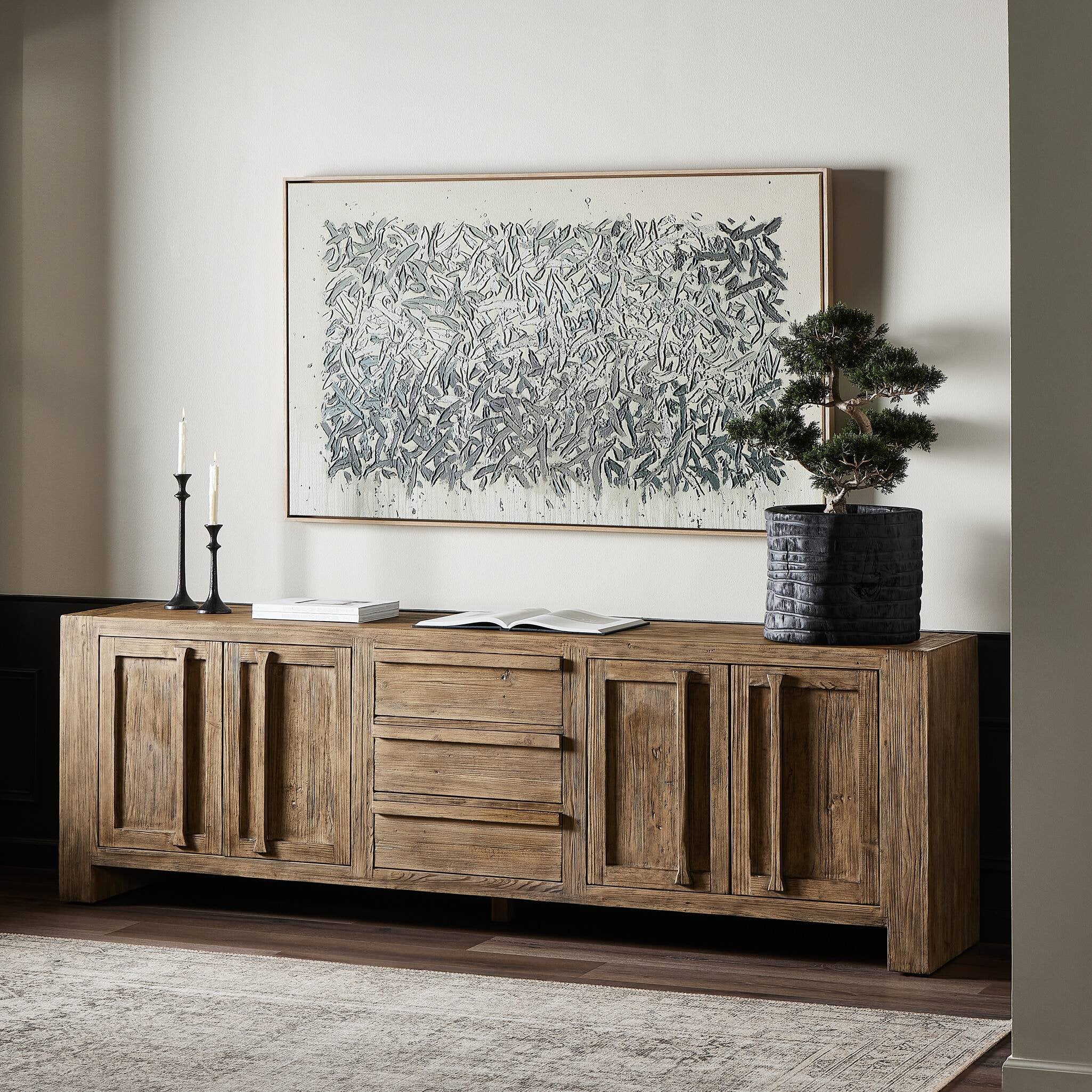 Wooden sideboard in a room with a large abstract painting on the wall.