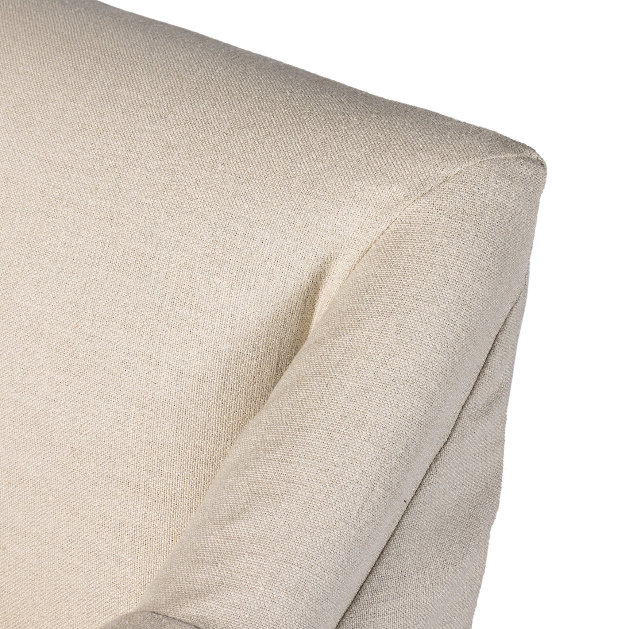 Close up of a natural slipcovered dining armchair detailing its fabric texture and rolled arms.