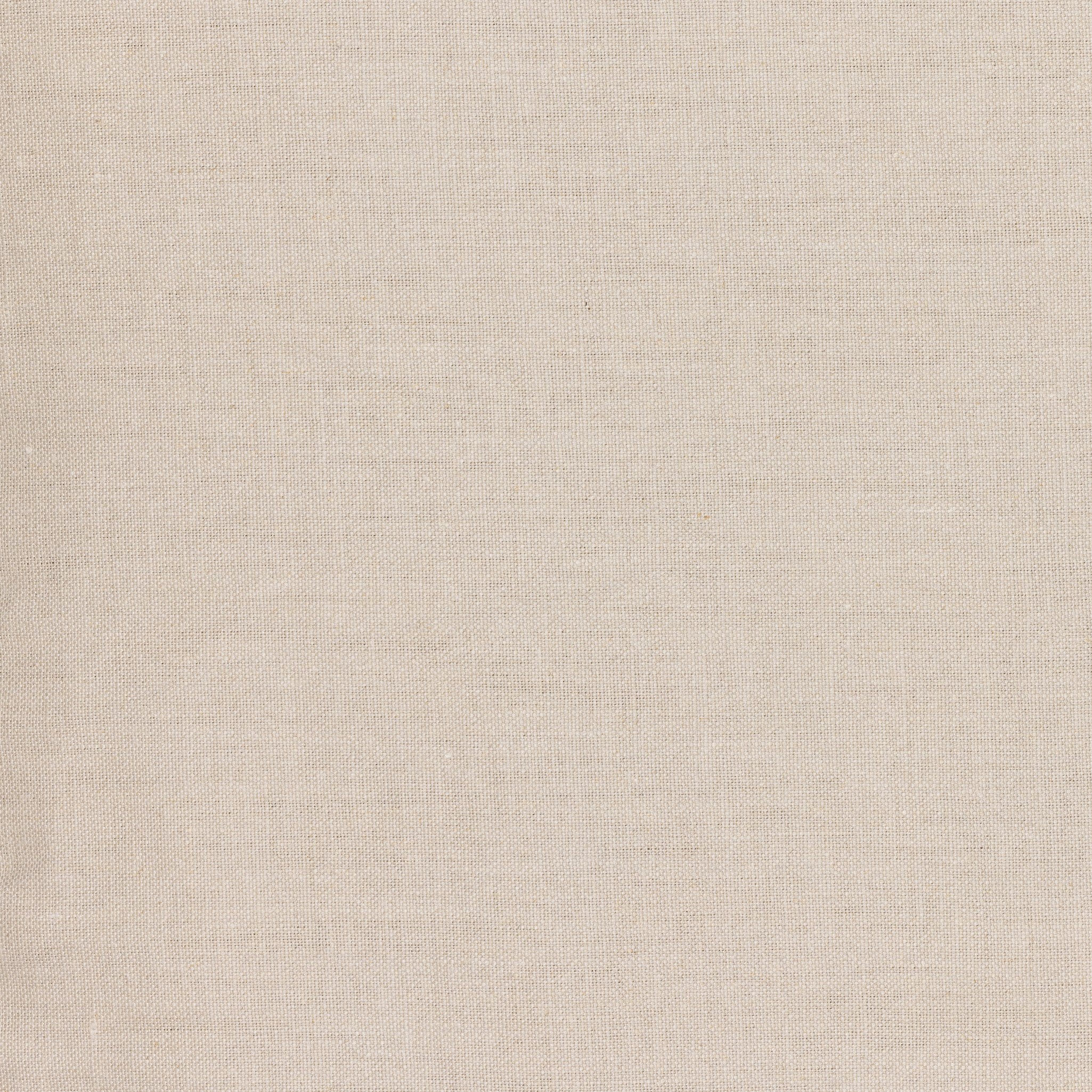 Close up of a natural slipcovered dining armchair with rolled arms on a white background.