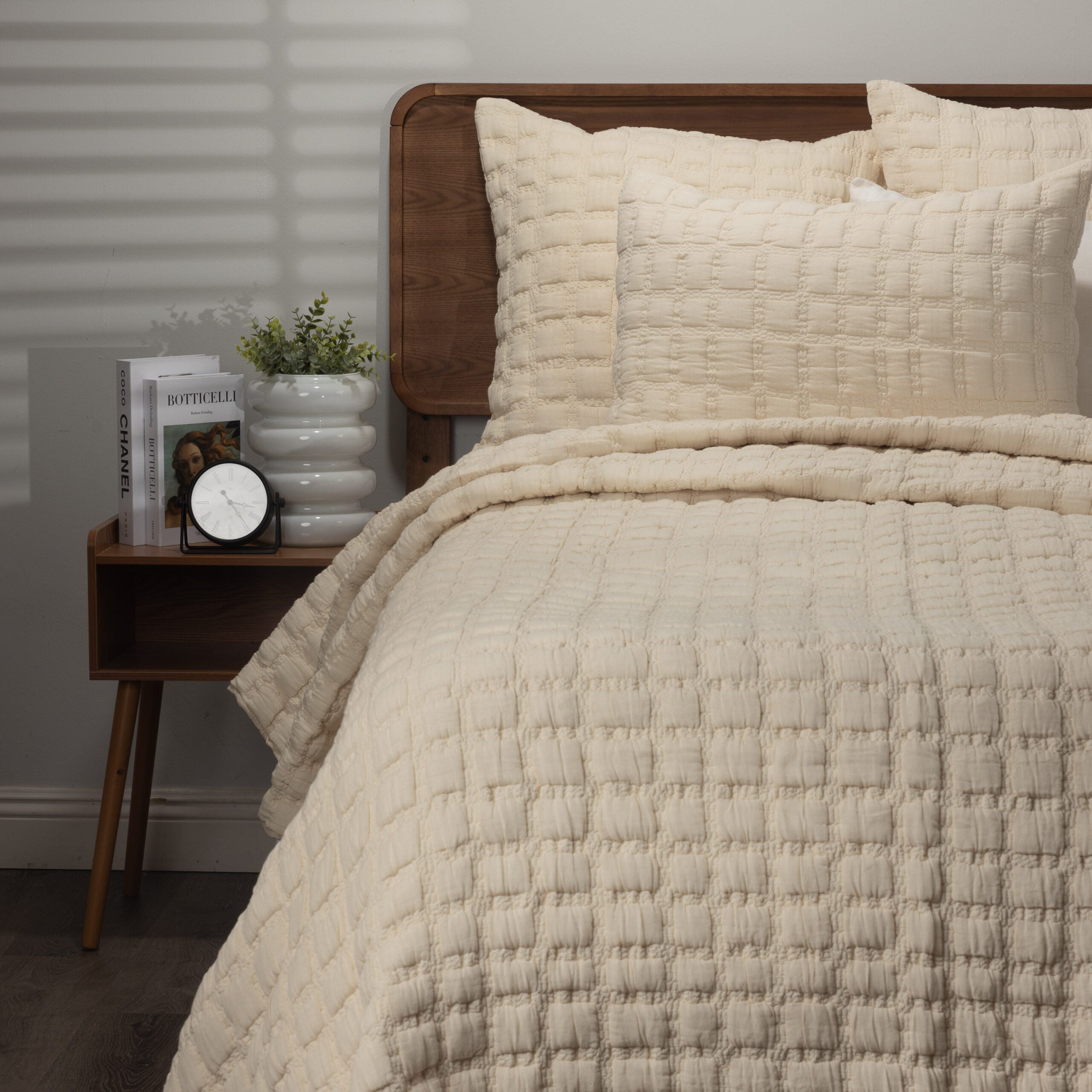 Styled cream quilt on bed with matching shams, showcasing its pillowy grid pattern and cozy layering.