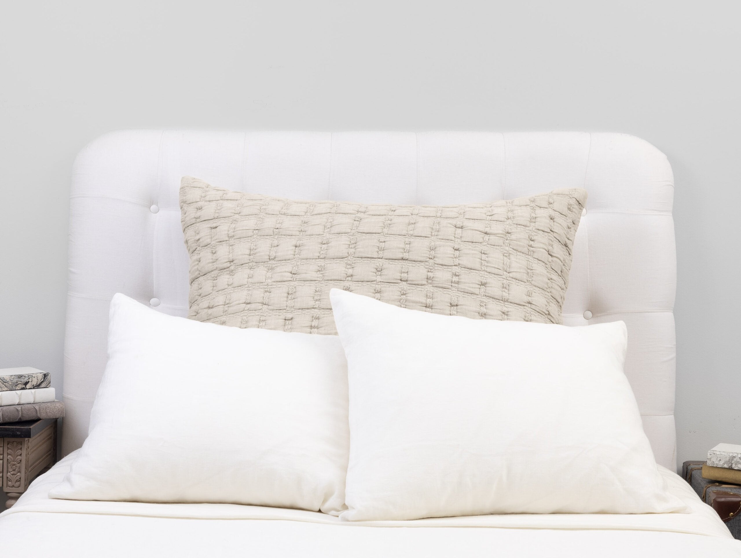 Beige sham styled with white pillows, showing its structured texture and refined grid quilting.