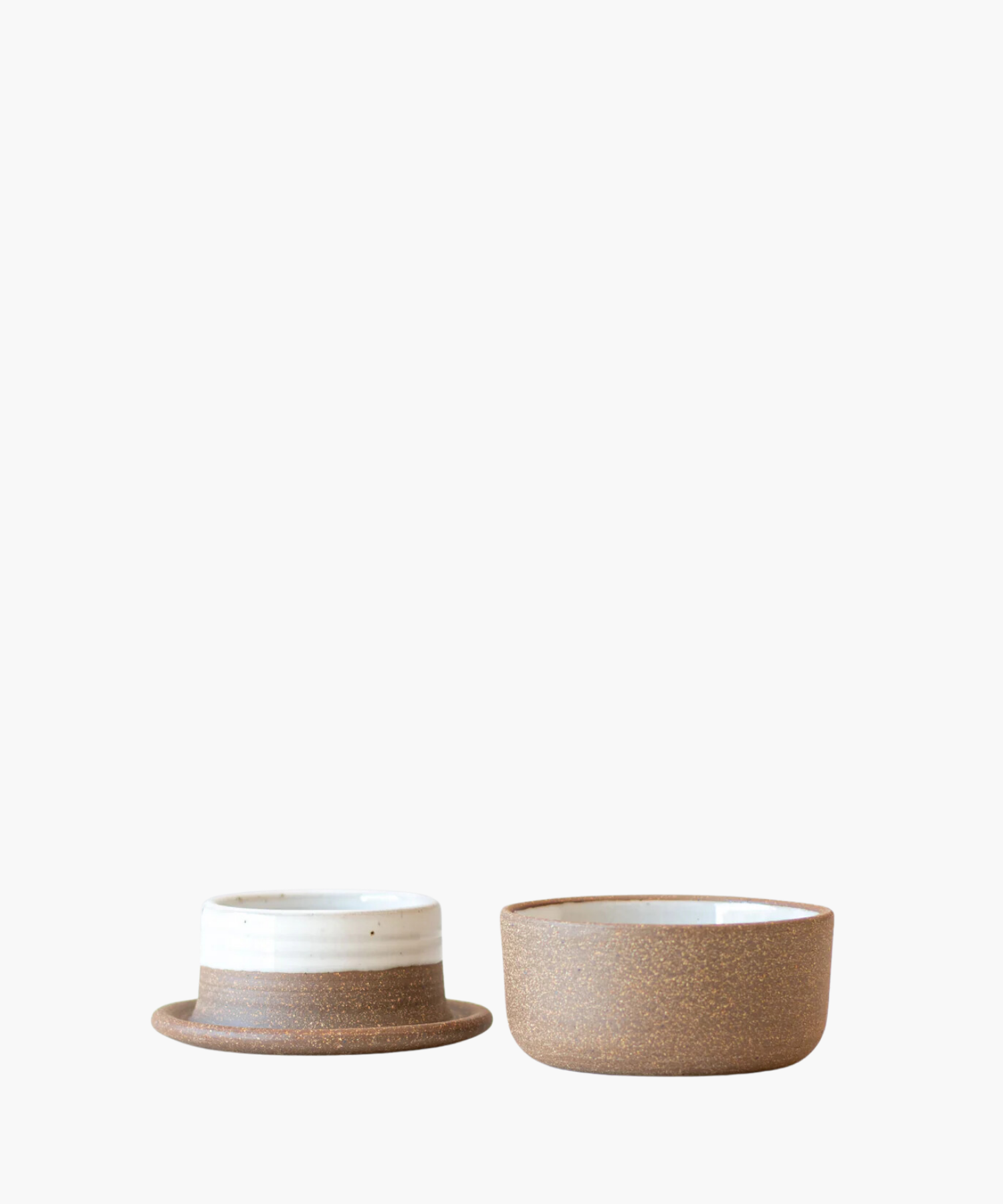 Ceramic butter keeper with minimalist design. The left is shorter with a wider rim and white top band. The right is taller, plain brown, on a white background.