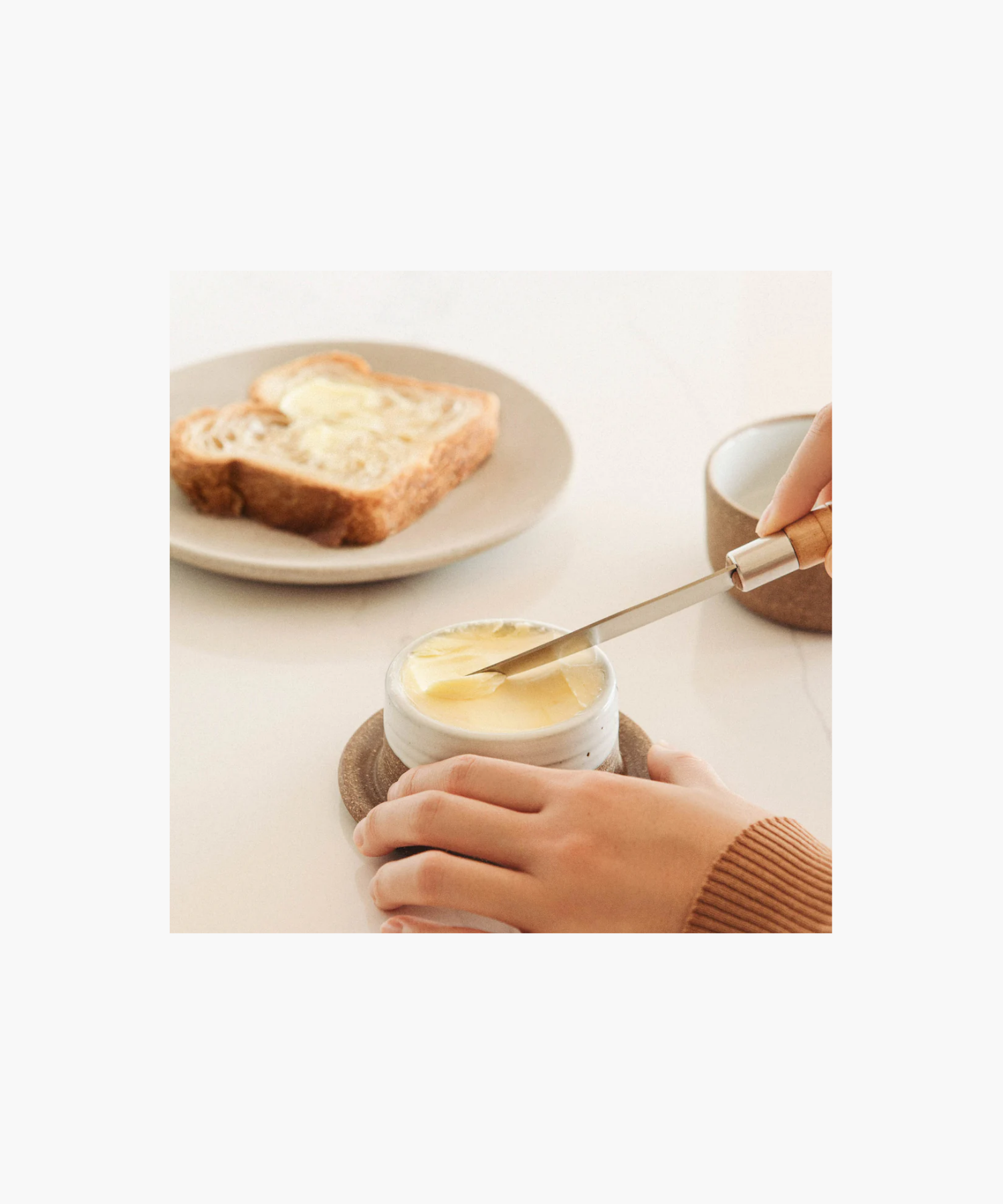 Ceramic butter keeper styled with bread and butter showing a minimalist design.