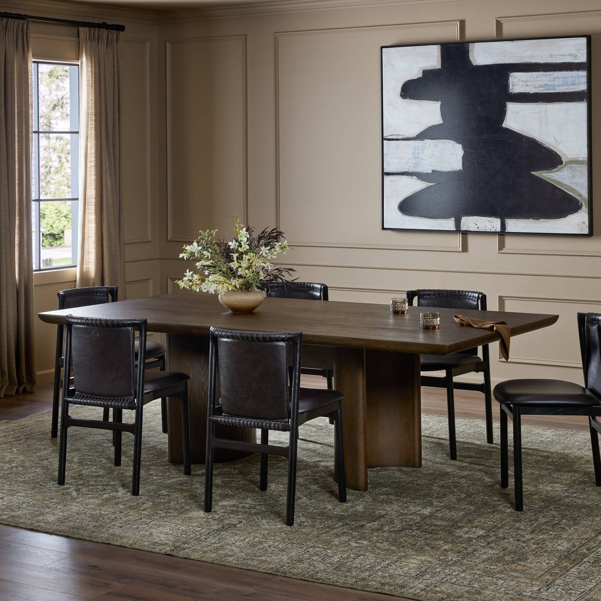Dining room with wooden table and black chairs, abstract painting on the wall.