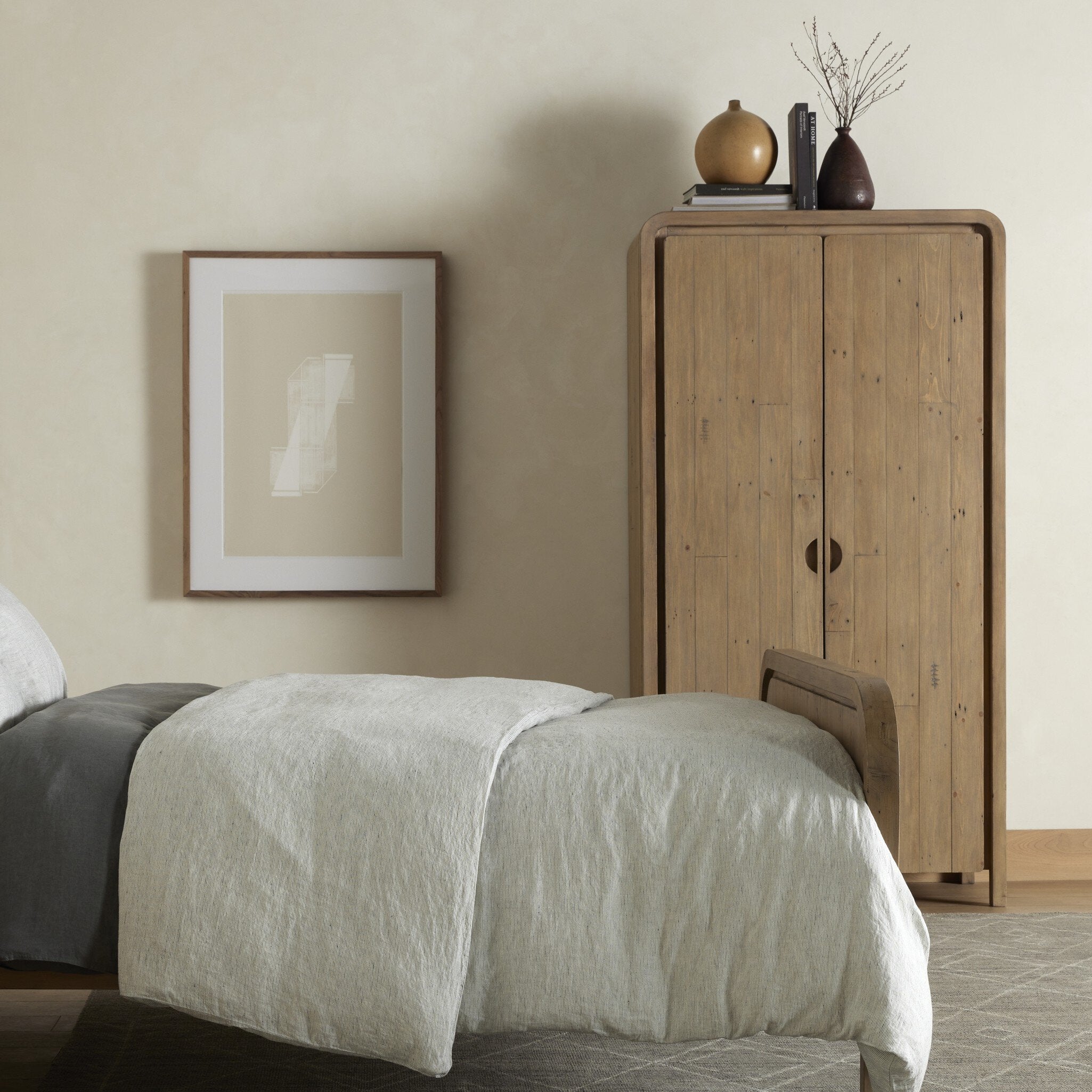 Bedroom with wooden wardrobe and framed artwork on beige wall