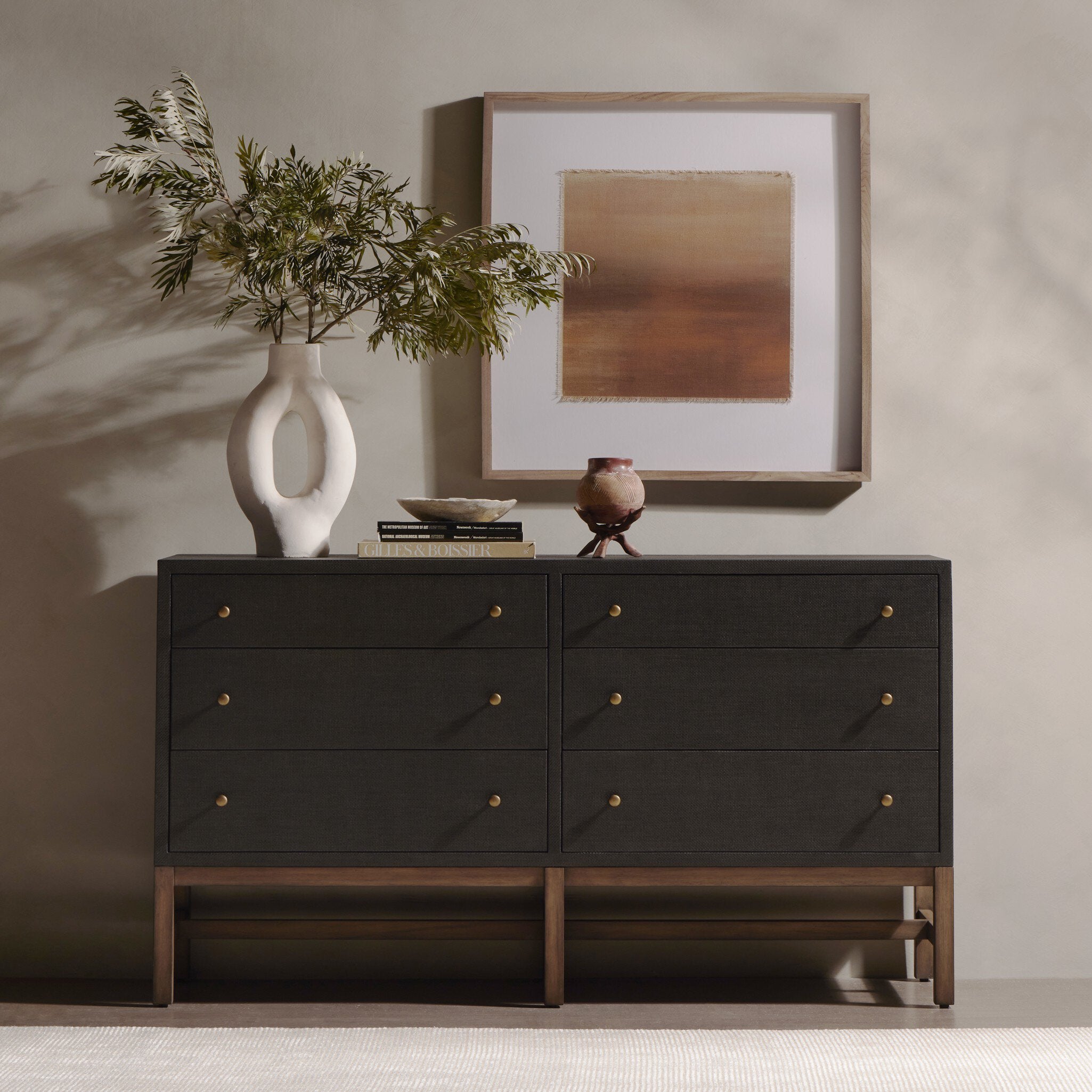 Dark wooden dresser with decorative items including a vase and framed artwork in a room.