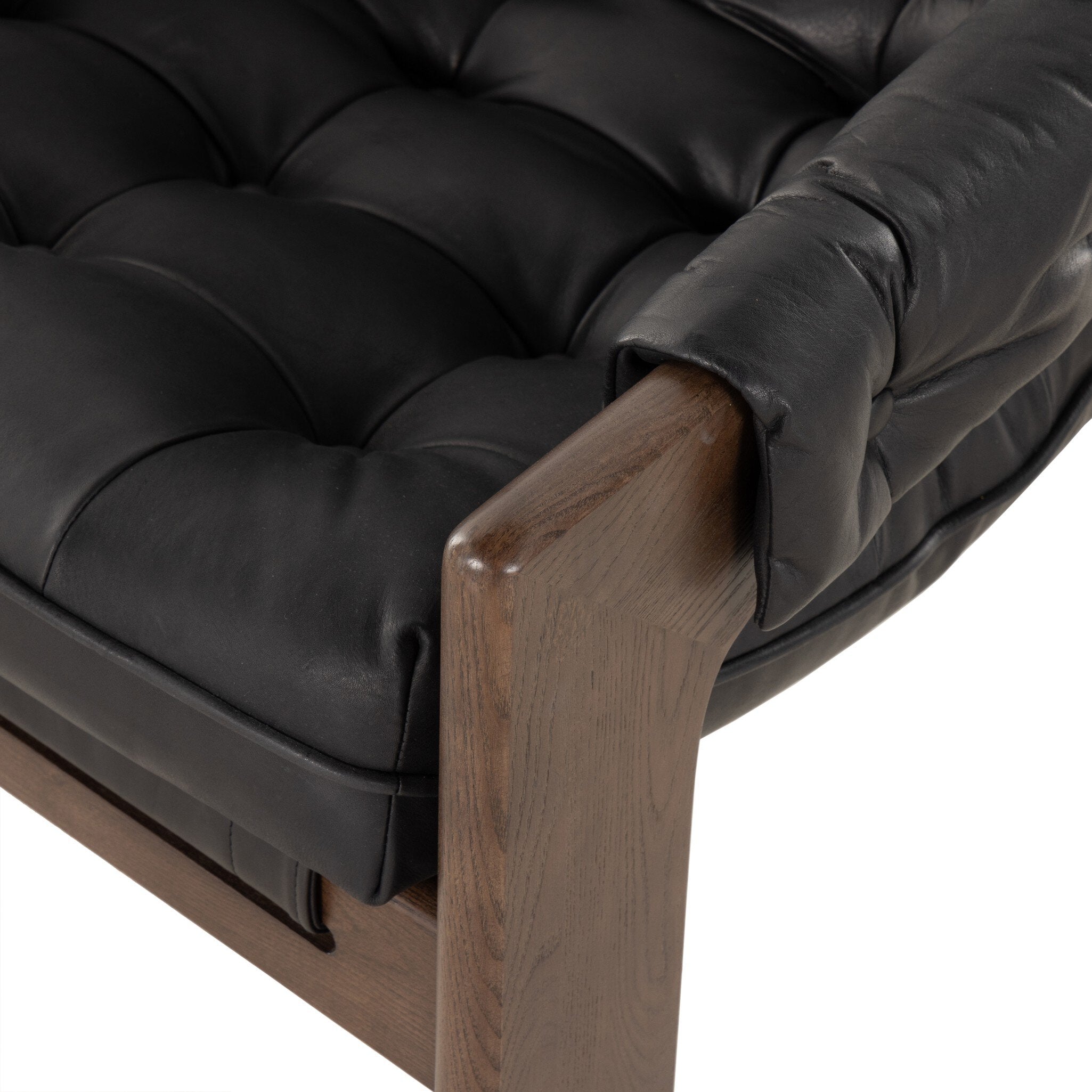 Tufted black leather sling style armchair with wooden frame on a white background.