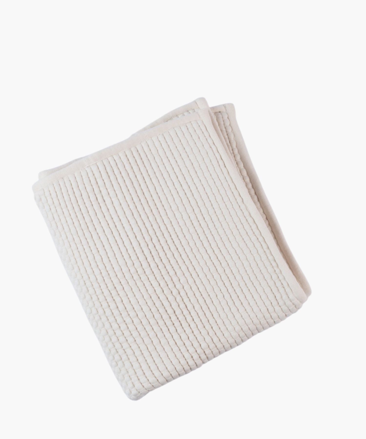 Folded ivory coverlet on a white background highlighting quilted or woven texture and soft, tonal color.