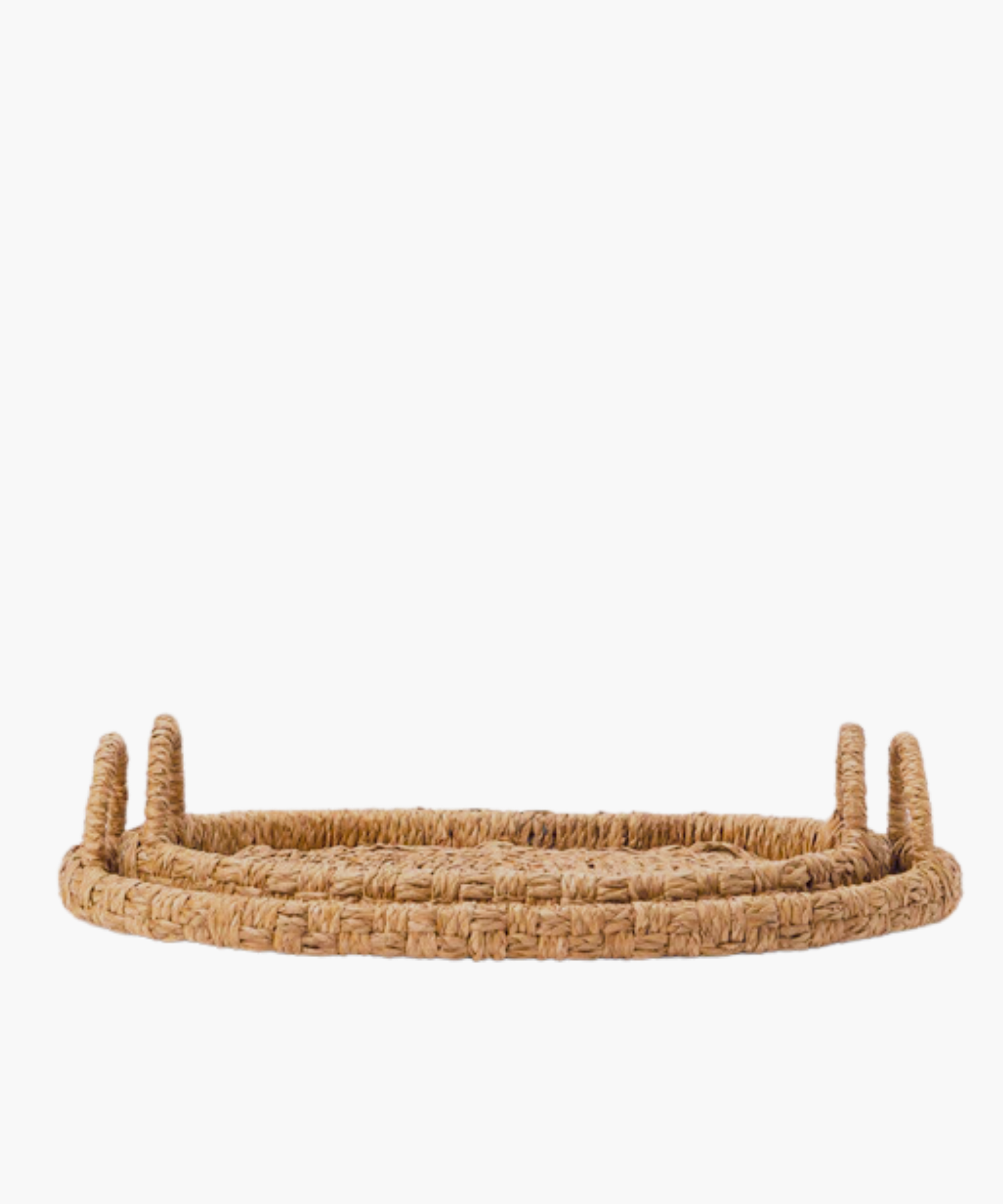 Oval hand-woven seagrass and rattan trays or baskets with two looped handles on each side in natural brown tones in two sizes. The tightly woven pattern suggests a sturdy, rustic style, suitable for home decor.