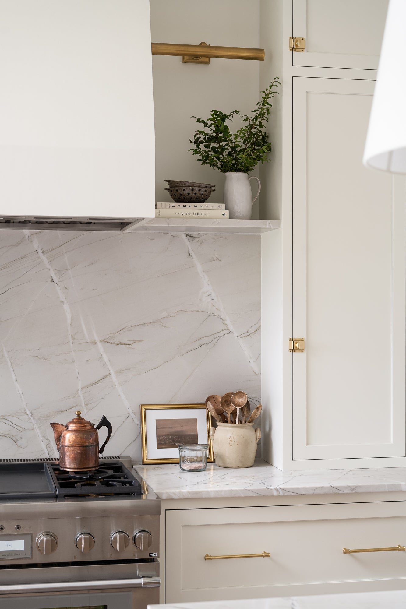 Ceramic colander or berry bowl with a rustic design, featuring a speckled brown glaze and evenly spaced holes. Styled in a simple neutral tone kitchen on a shelf with books. It conveys a handcrafted, earthy aesthetic.