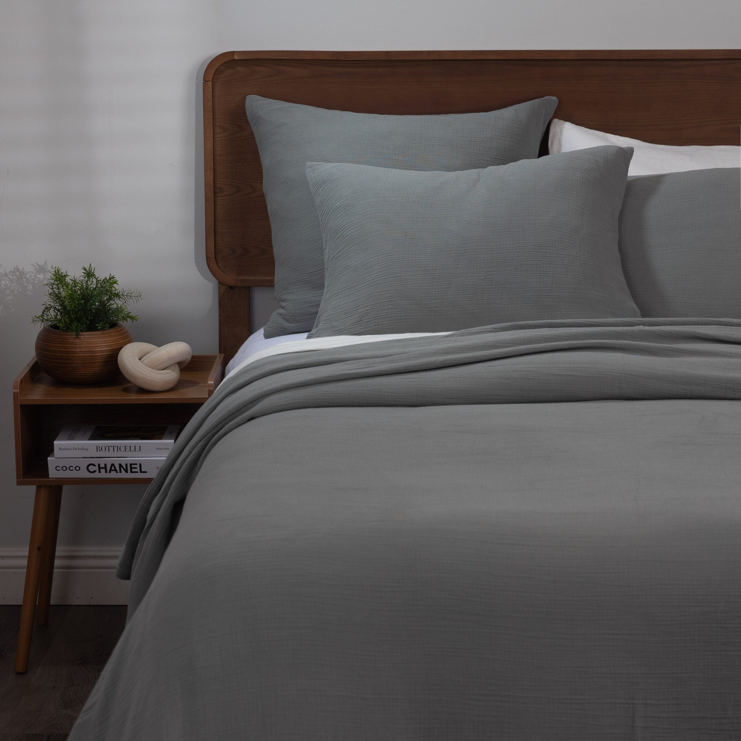Bed styled with the soft gray Jenski duvet cover and shams with a subtle crinkle texture, paired with wood furniture for a grounded, modern look.