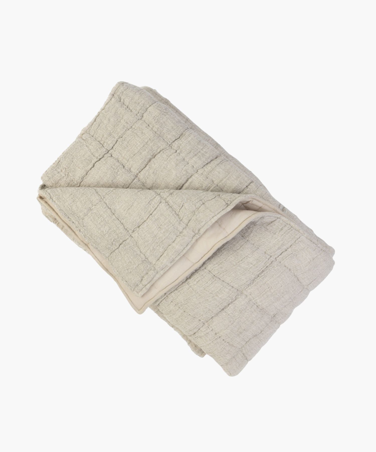 Folded beige cotton-linen blend quilt on a white background showing its puckered texture and hand-stitched block pattern.