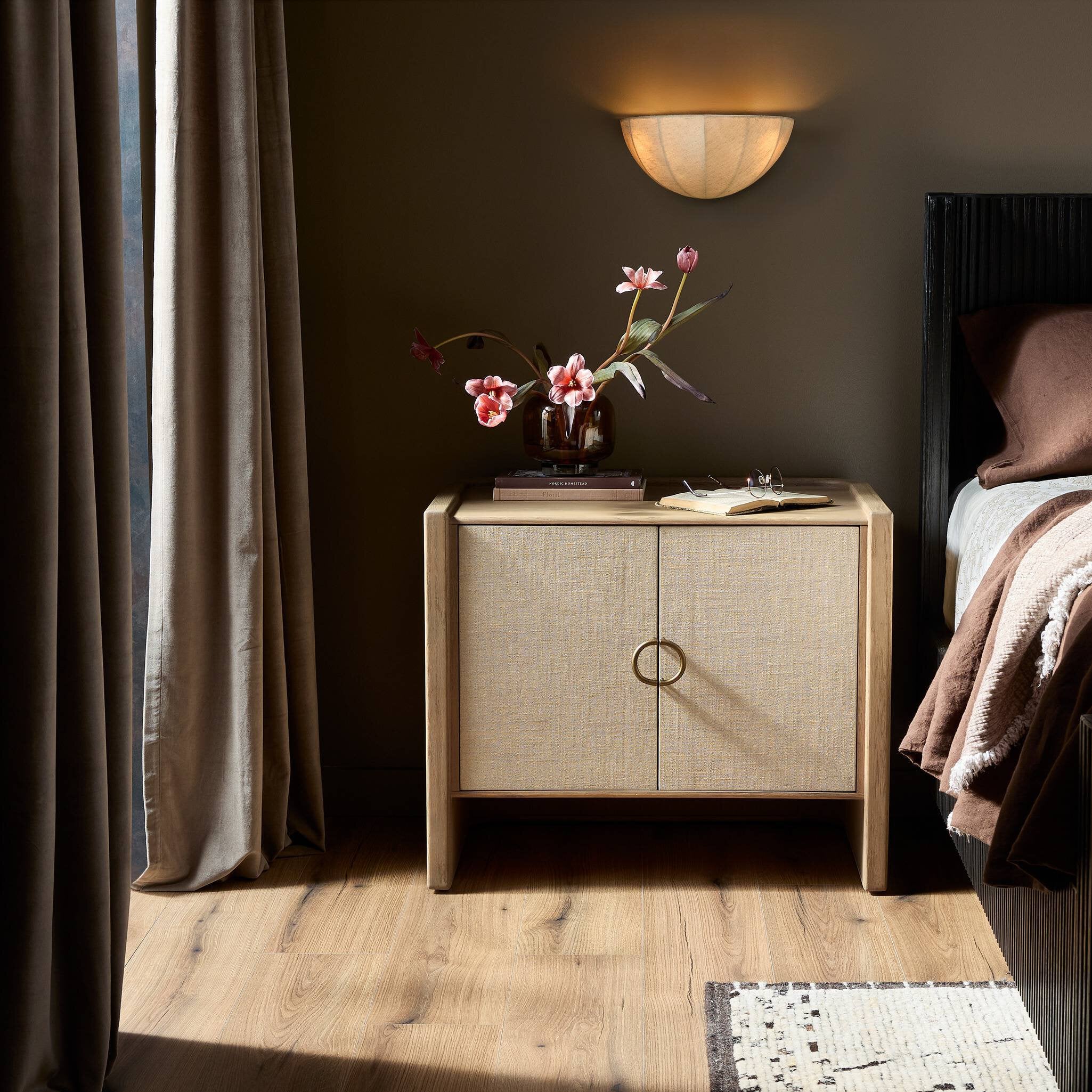 Wooden nightstand with floral arrangement in a bedroom setting