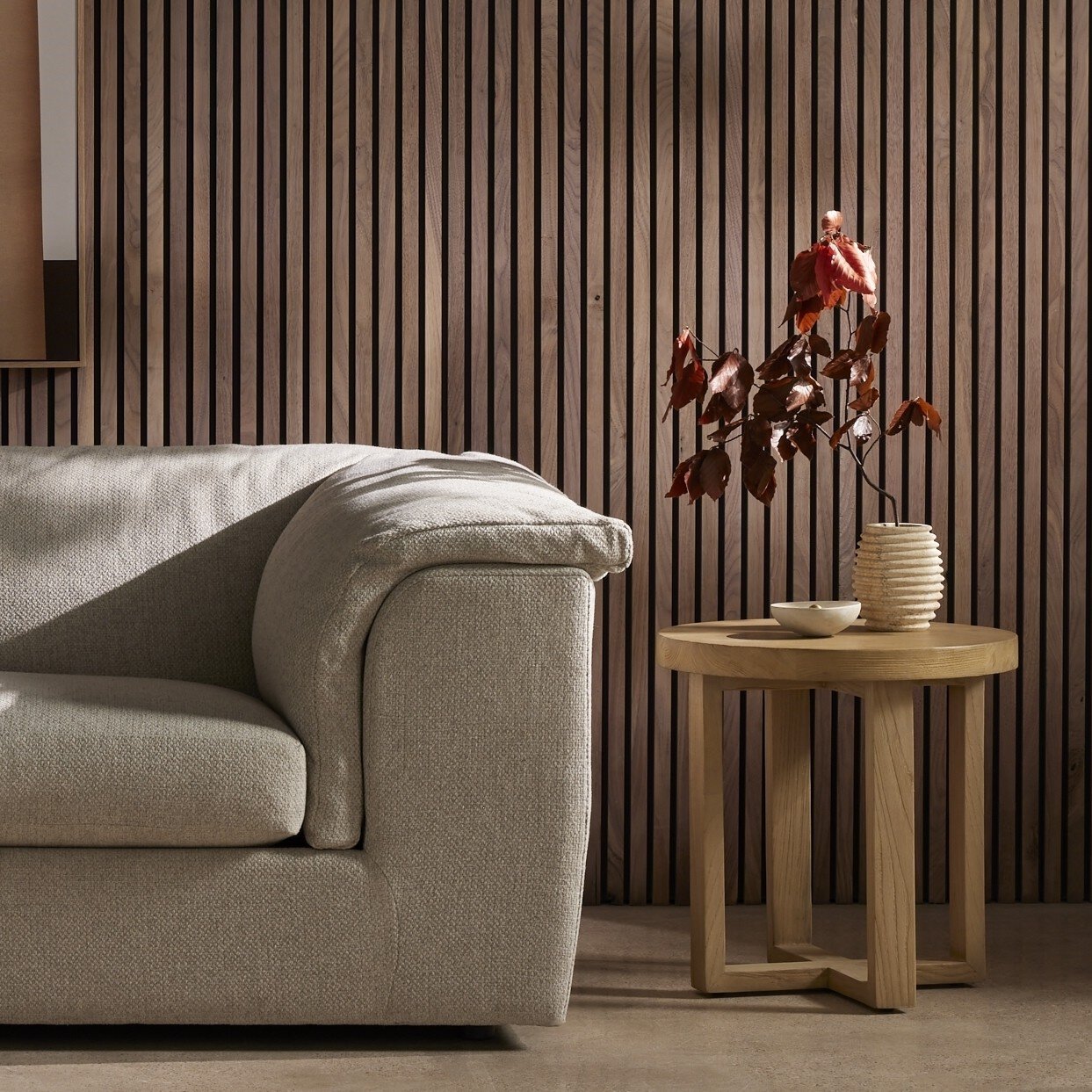 Beige sofa in a room with wooden side table and decorative plant against striped wall.