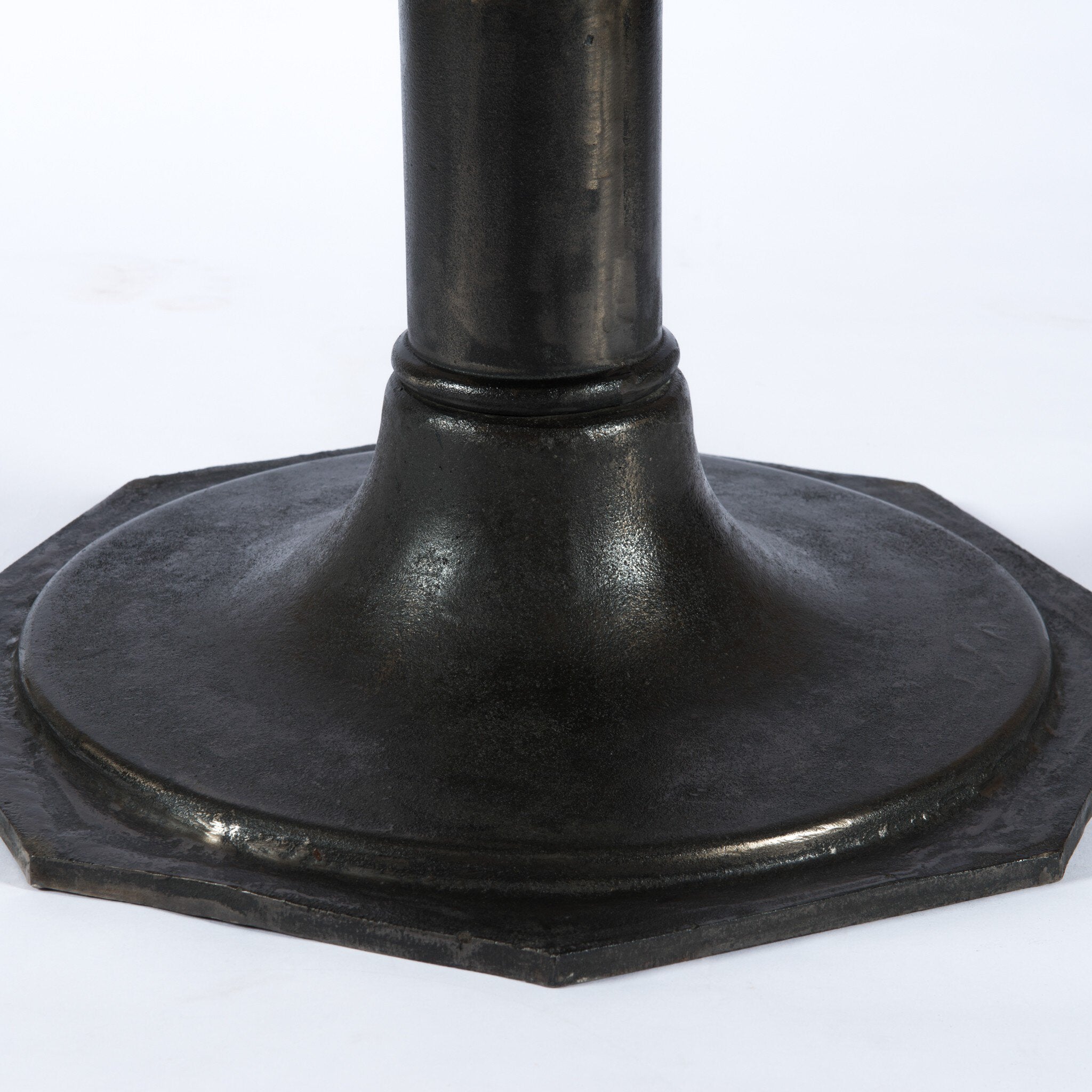 Close up of a round marble dining table with a black metal pedestal base on a white background.
