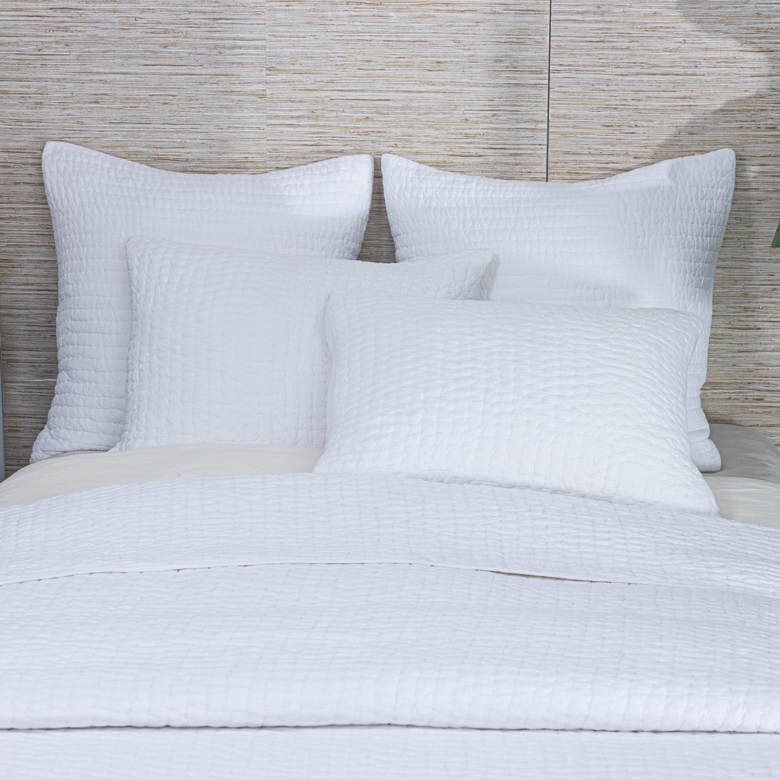 Styled Maegan Quilt on a bed, layered with matching shams and pillows, emphasizing its artisanal stitching and soft drape.