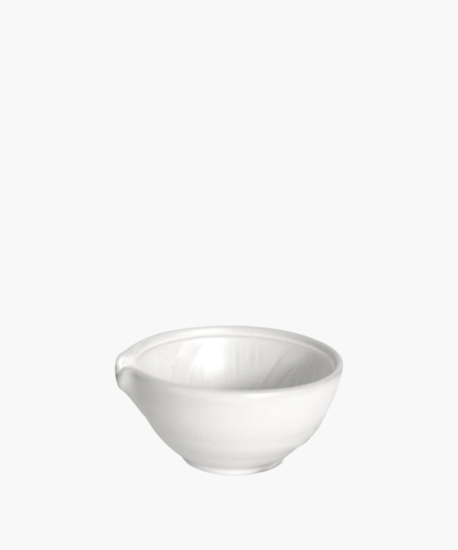 Simple white ceramic mixing bowl with a small spout, reflecting soft light. The bowl is placed against a plain, light gray background.