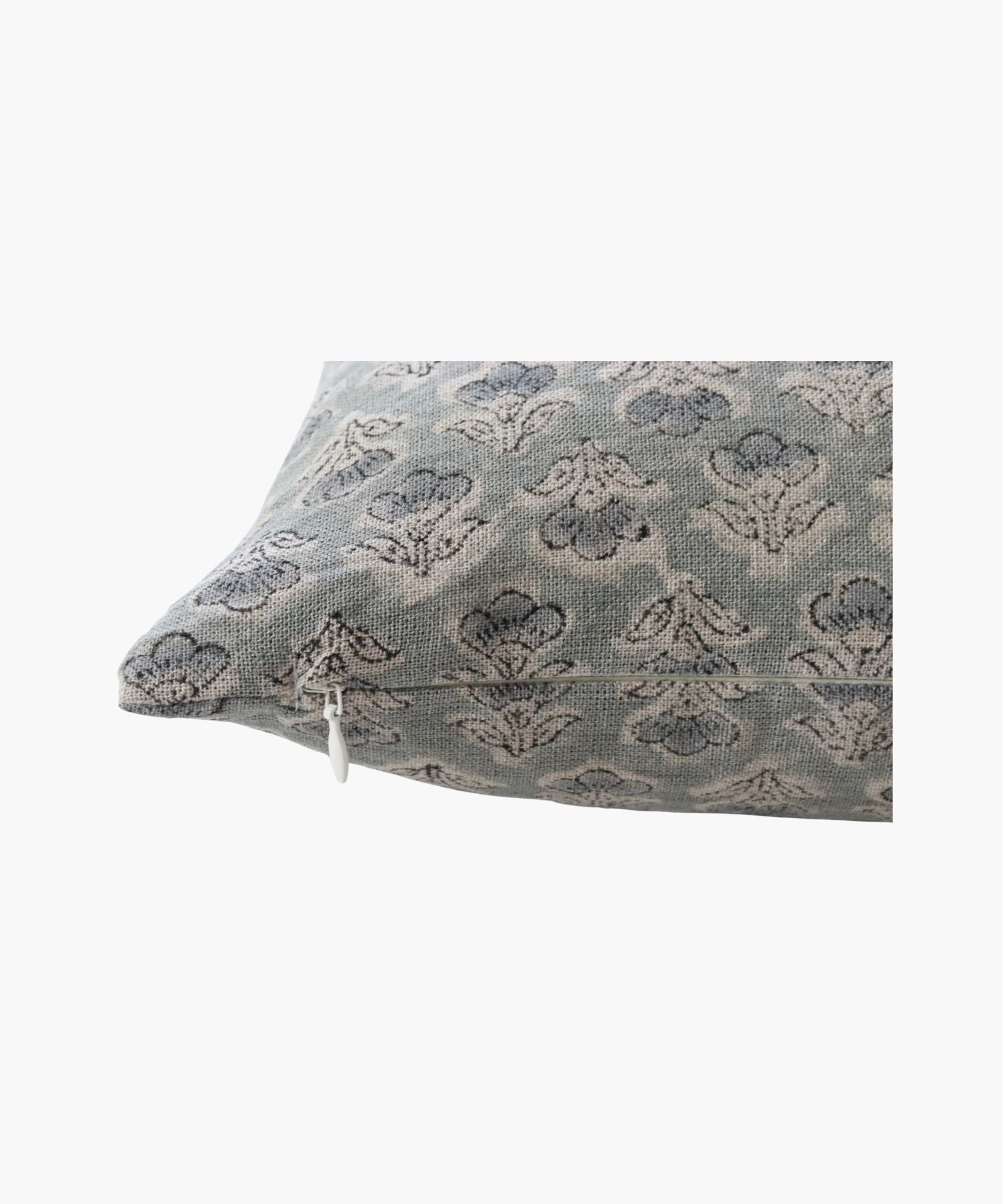 A close up of a pillow with a subtle, intricate floral pattern in muted blue and gray tones. The design is elegant, conveying a calm and cozy atmosphere.