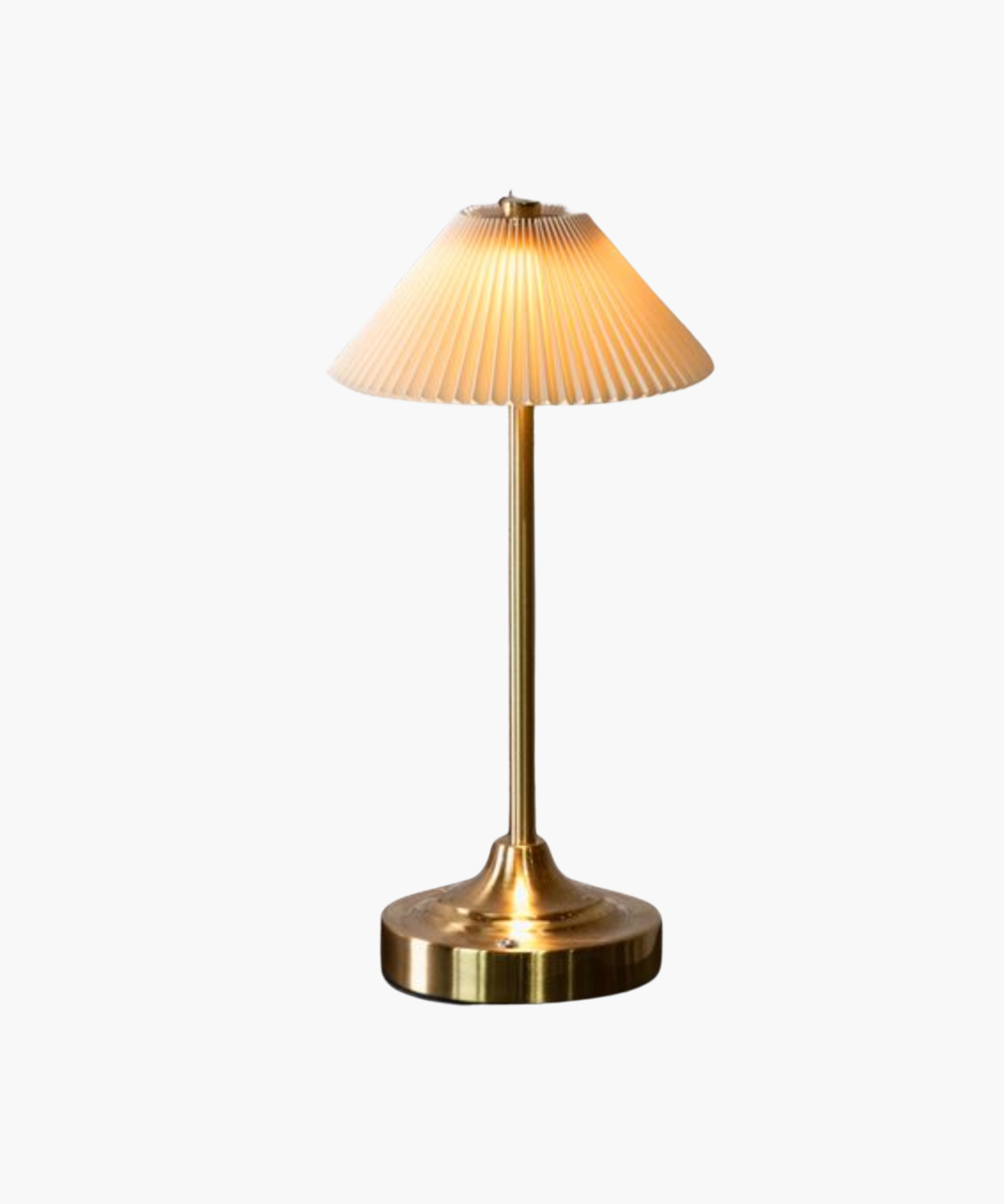 A warm, glowing brass table lamp with a fluted white shade sits on a reflective surface. The sleek design and soft lighting create an elegant and cozy ambiance.