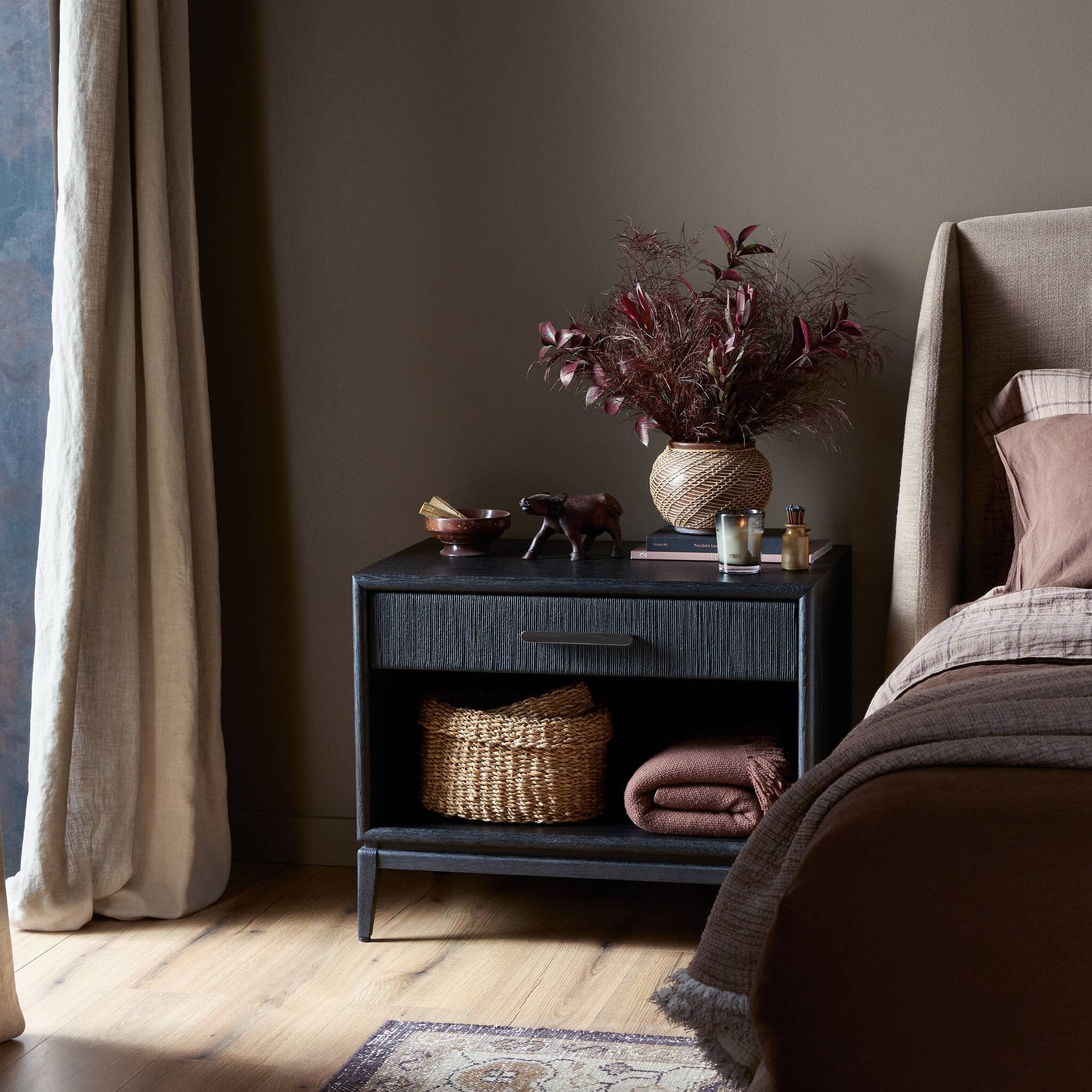 Nighstand with decorative items next to a bed in a bedroom setting