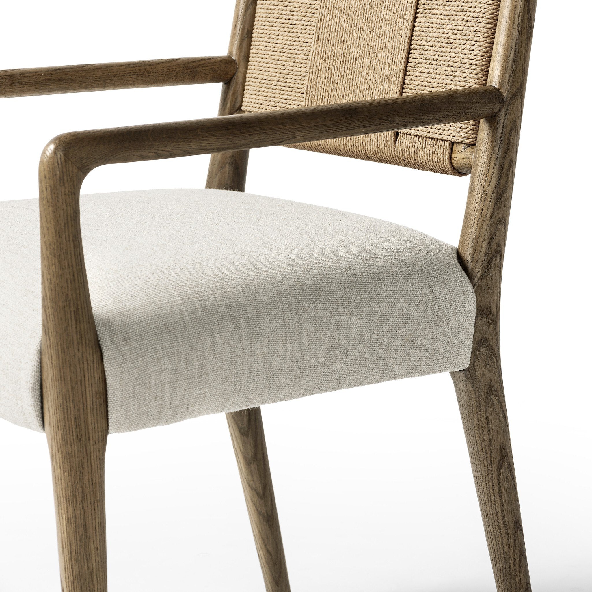 Close up of a dining chair with woven backrest and upholstered seat on a white background.