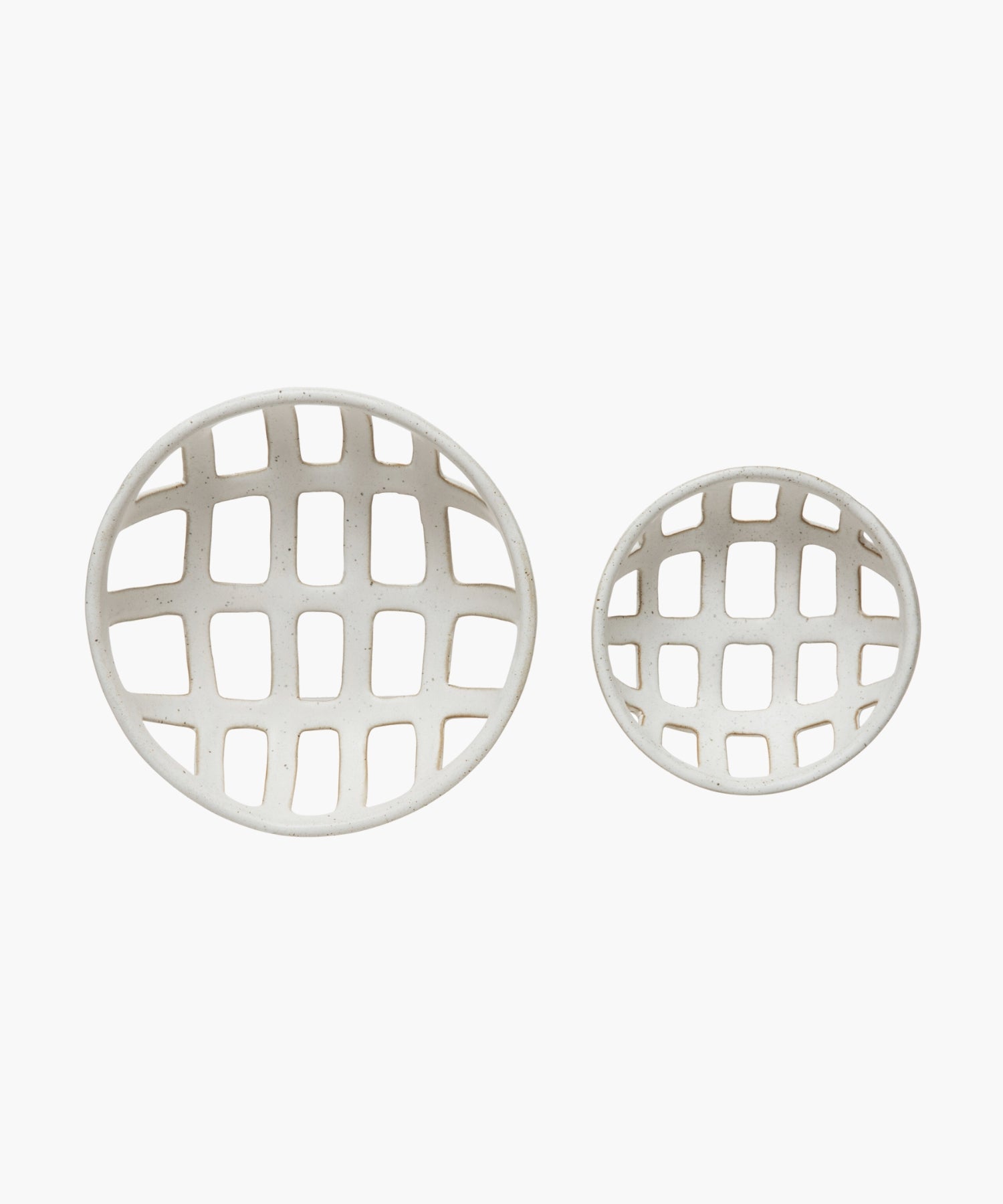 Overhead view of two openwork stoneware ceramic bowls with a white reactive glaze finish, one larger than the other, featuring an airy, lattice-like design. The tone is minimalist and modern.