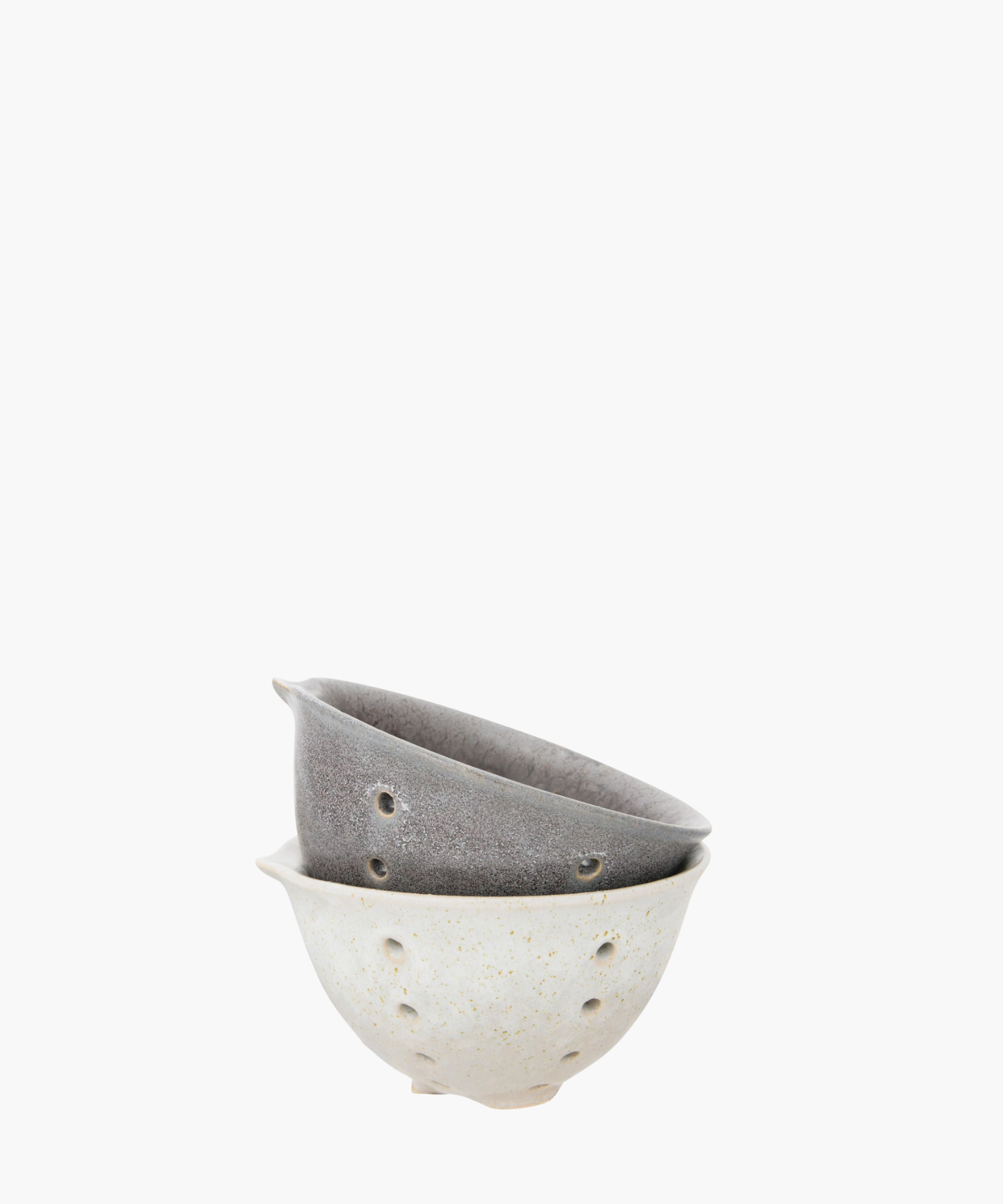 Two stacked ceramic bowls with small holes. The bottom bowl is light-colored with speckles, and the top bowl is a textured gray. Simple and artistic.