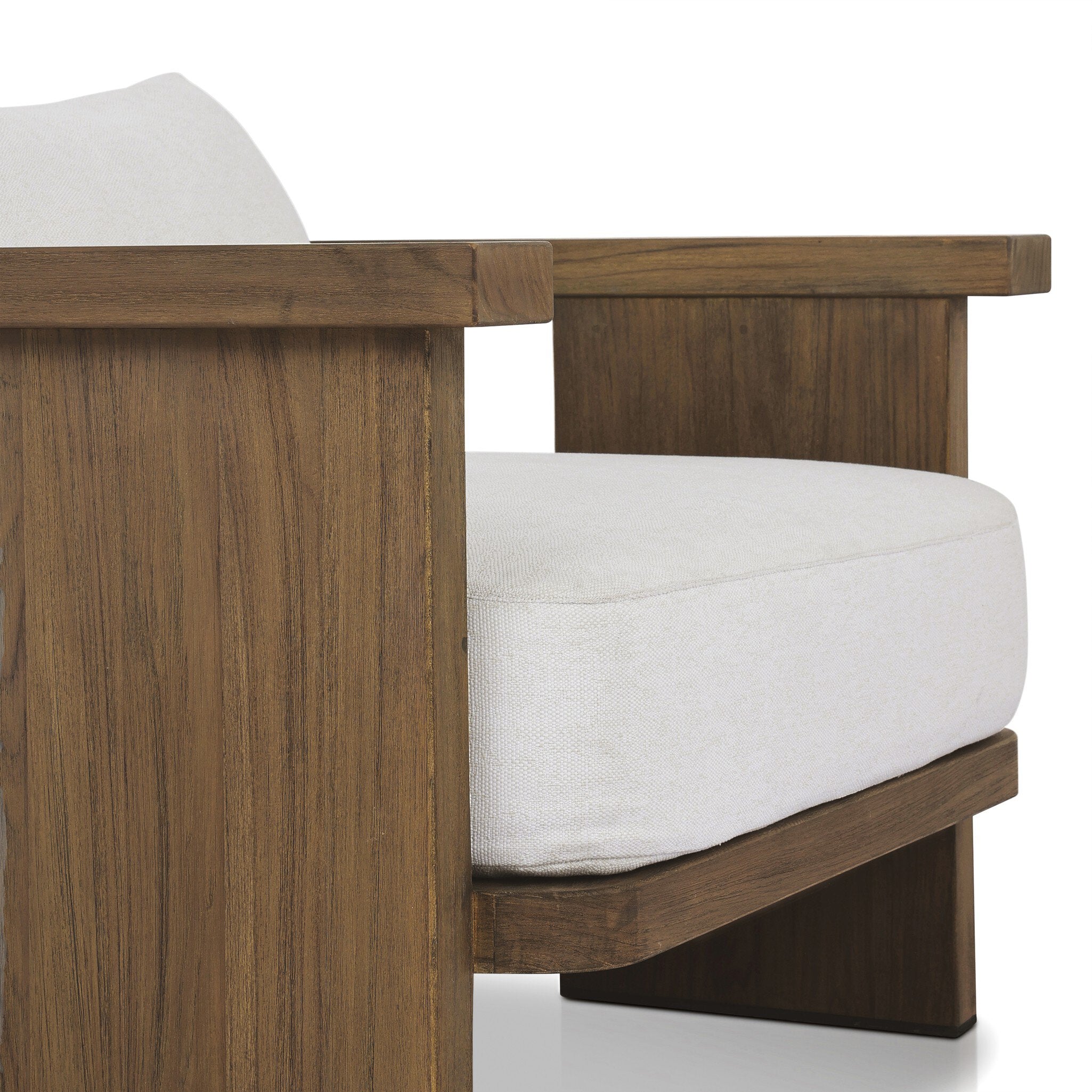 Close up view of an outdoor armchair with a curved wooden frame out of teak and white linen cushions on a white background.