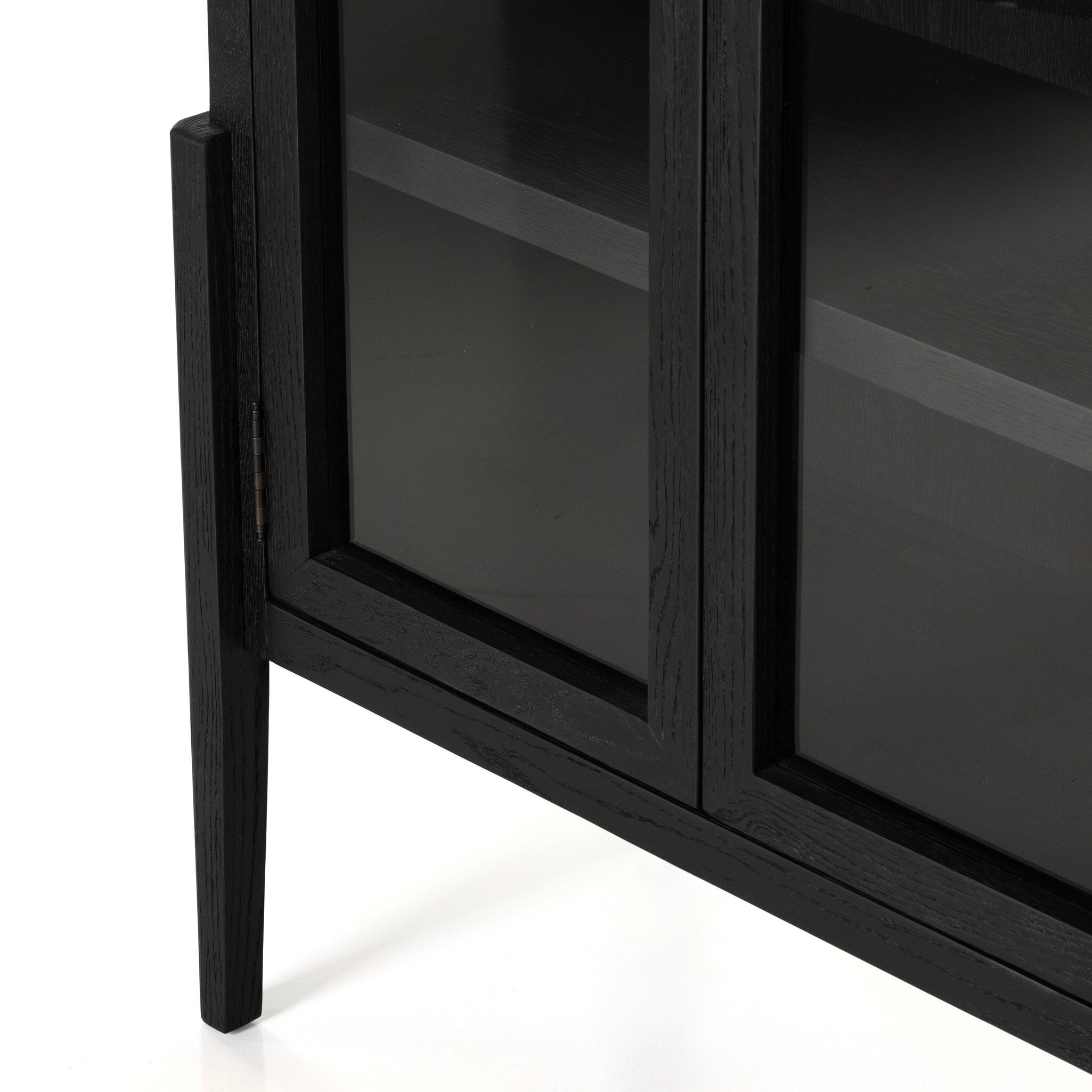 Close up of a black-finished solid oak cabinet with an arched top and glass doors.