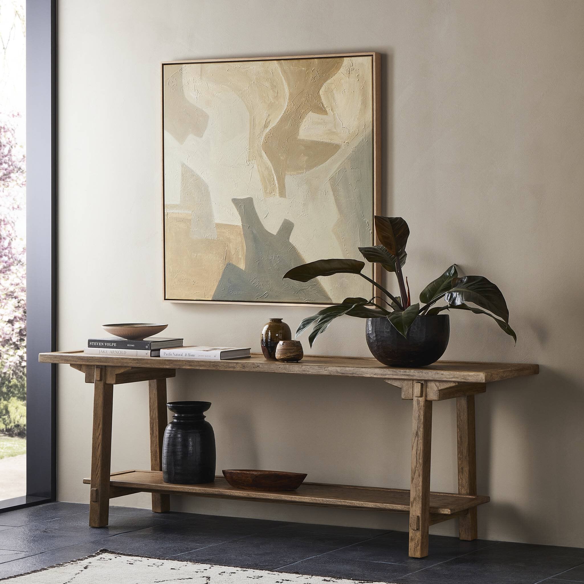Wooden console table with decorative items and a large abstract painting in a room.