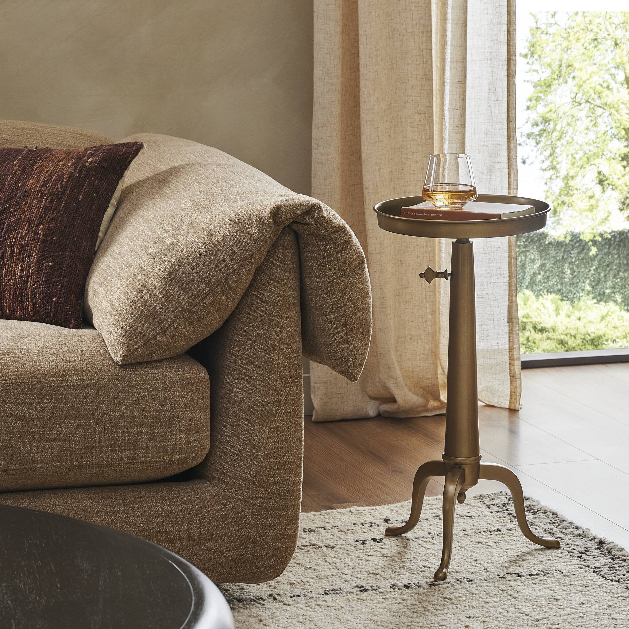 Beige sofa with a brass end table in a living room setting.