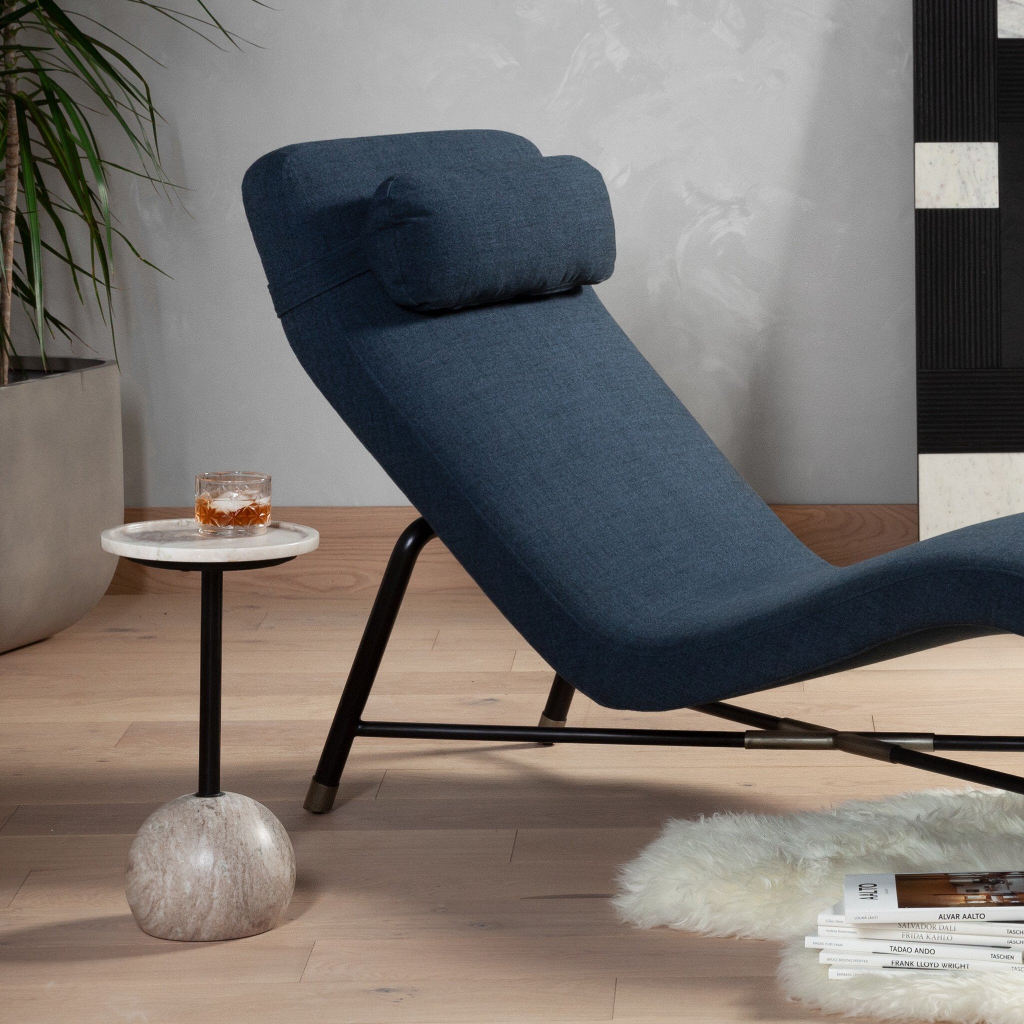 Blue lounge chair in a modern living room setting with a side table and books.