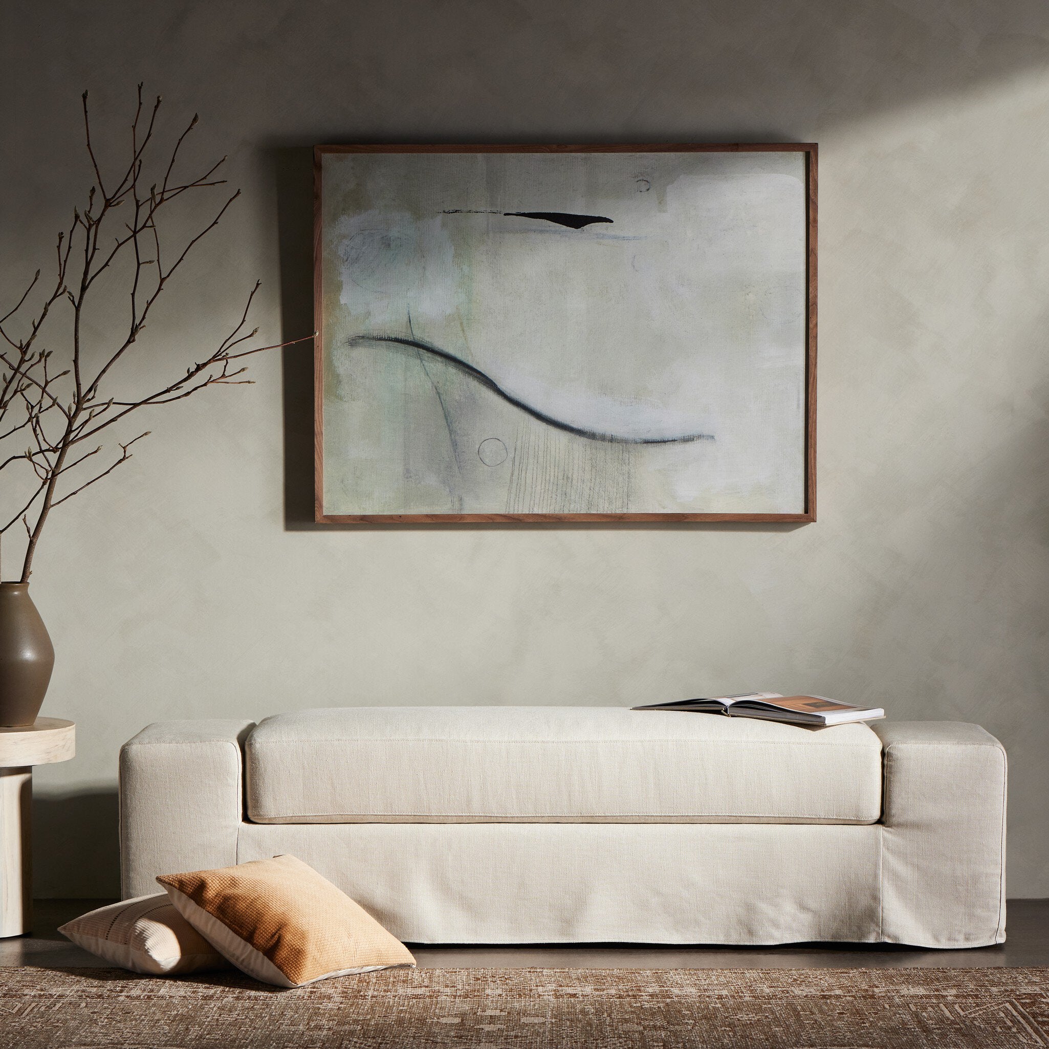 Ivory accent bench with a vase and abstract painting in a room setting.