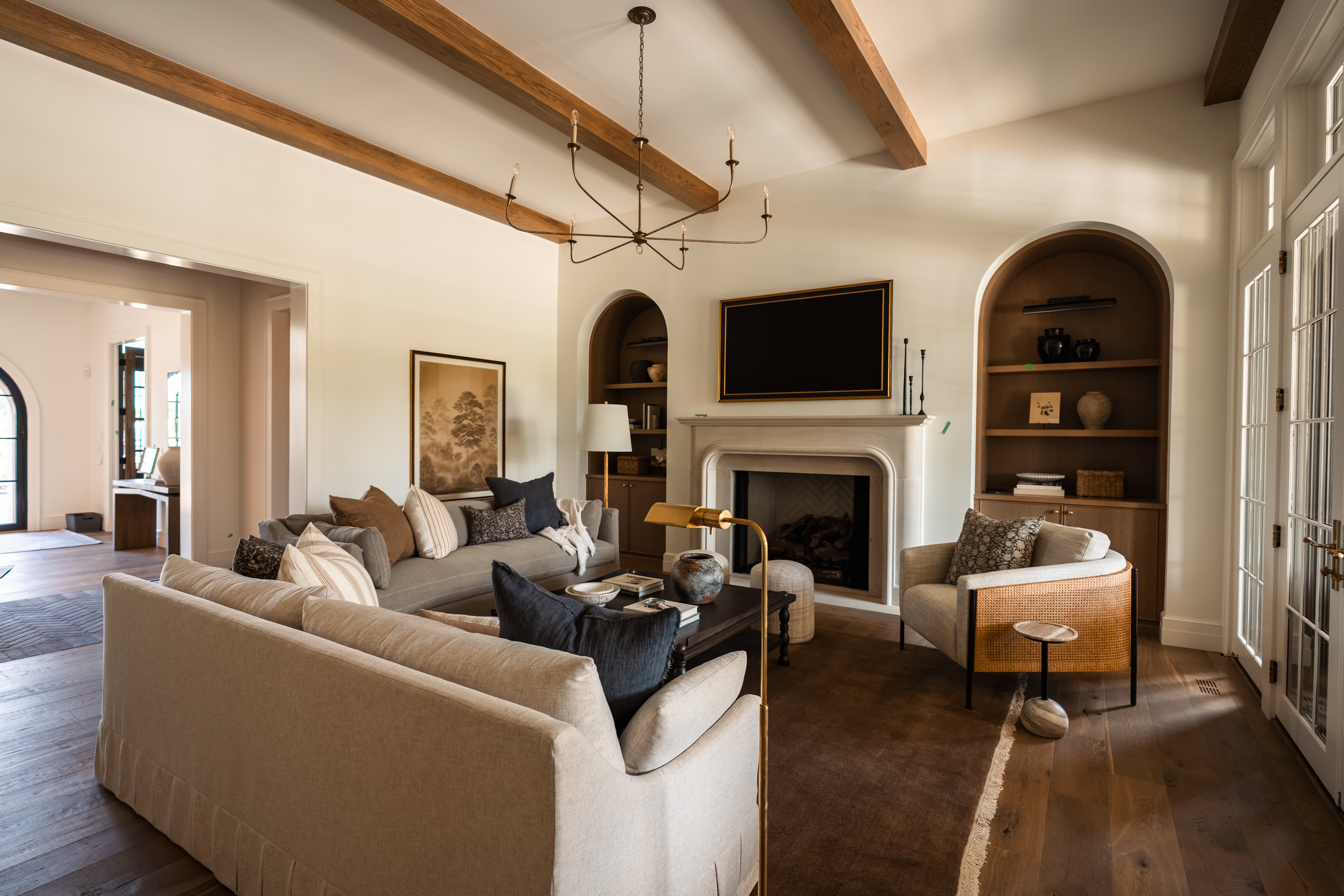 Living room with beige sofa, wooden beams, and a fireplace.