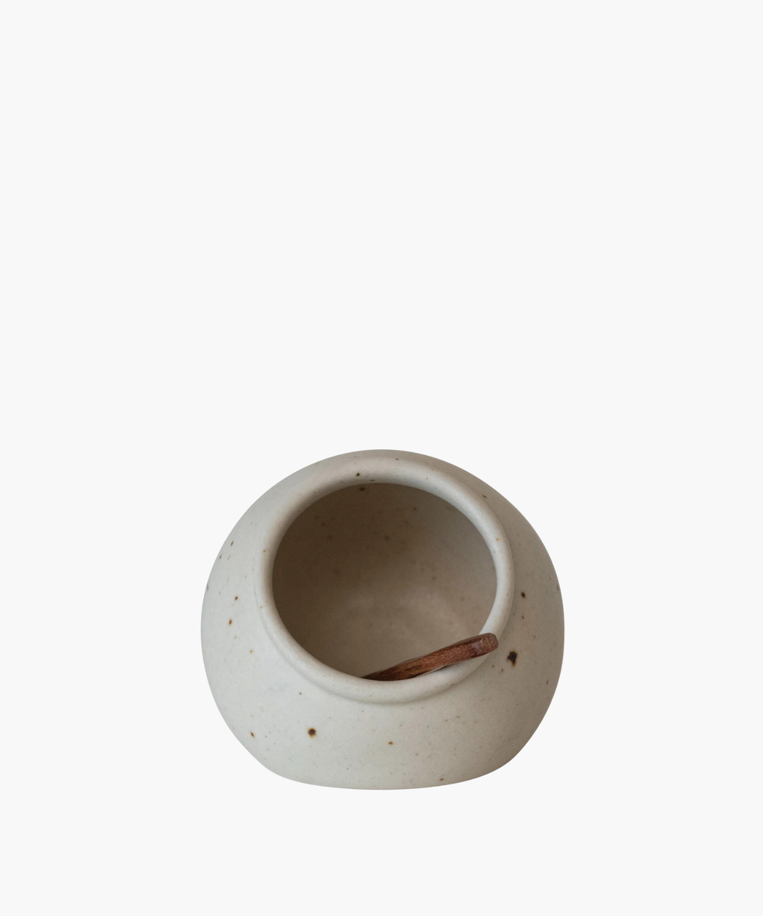 Creamy, speckled ceramic salt cellar with a small wooden scoop inside, evoking a rustic, minimalist aesthetic. The bowl's simple elegance suggests calm.