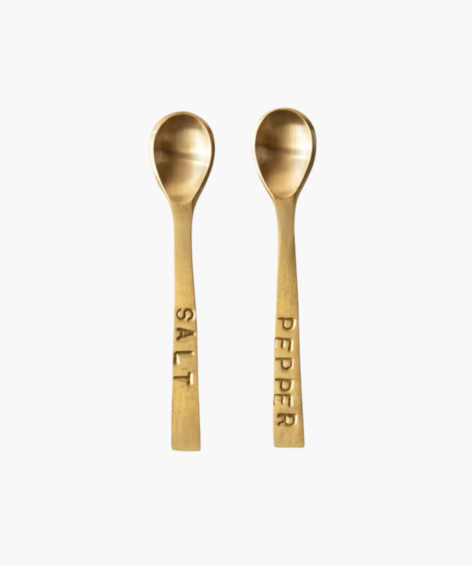 Two small elegant gold-toned spoons with engraved labels, "SALT" and "PEPPER," on their handles, set against a white background, conveying sophistication.