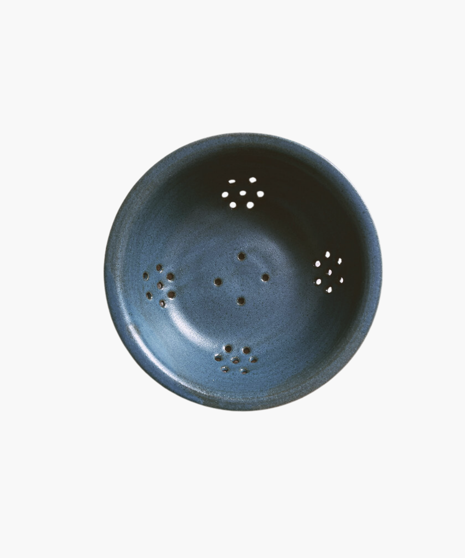 Blue ceramic colander with a smooth finish, featuring multiple small drainage holes arranged symmetrically. The tone is simple and functional.
