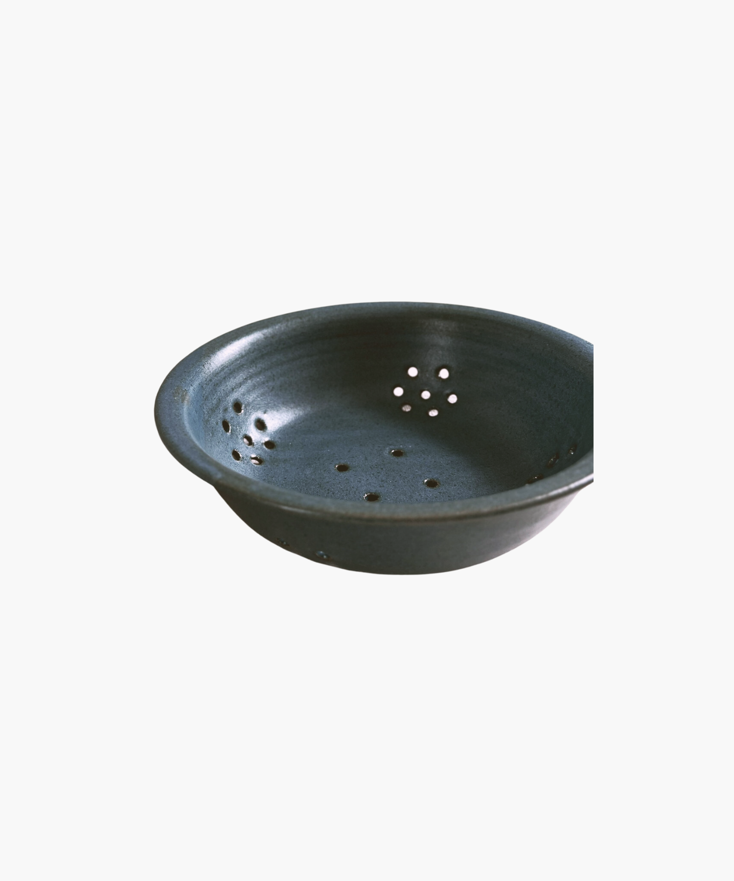 Blue ceramic colander with a smooth finish, featuring multiple small drainage holes arranged symmetrically. The tone is simple and functional.