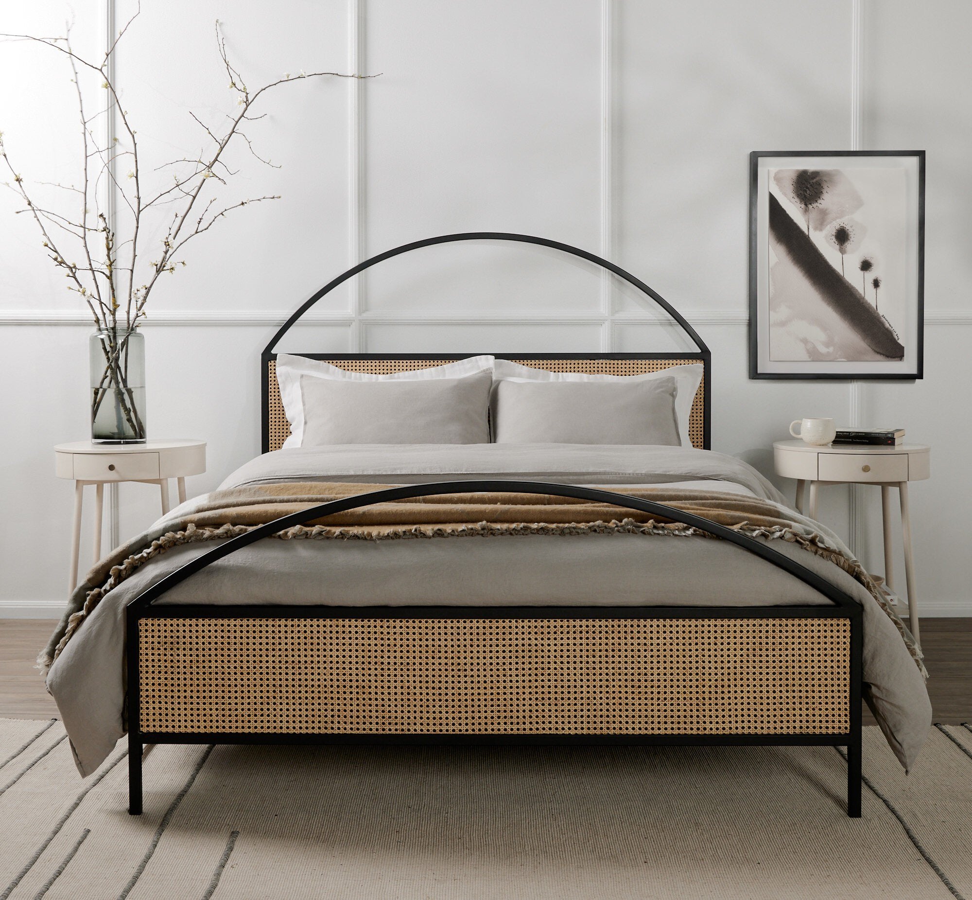 Bedroom with a bed featuring a wicker headboard and footboard, white bedding, and a side table with decor items.