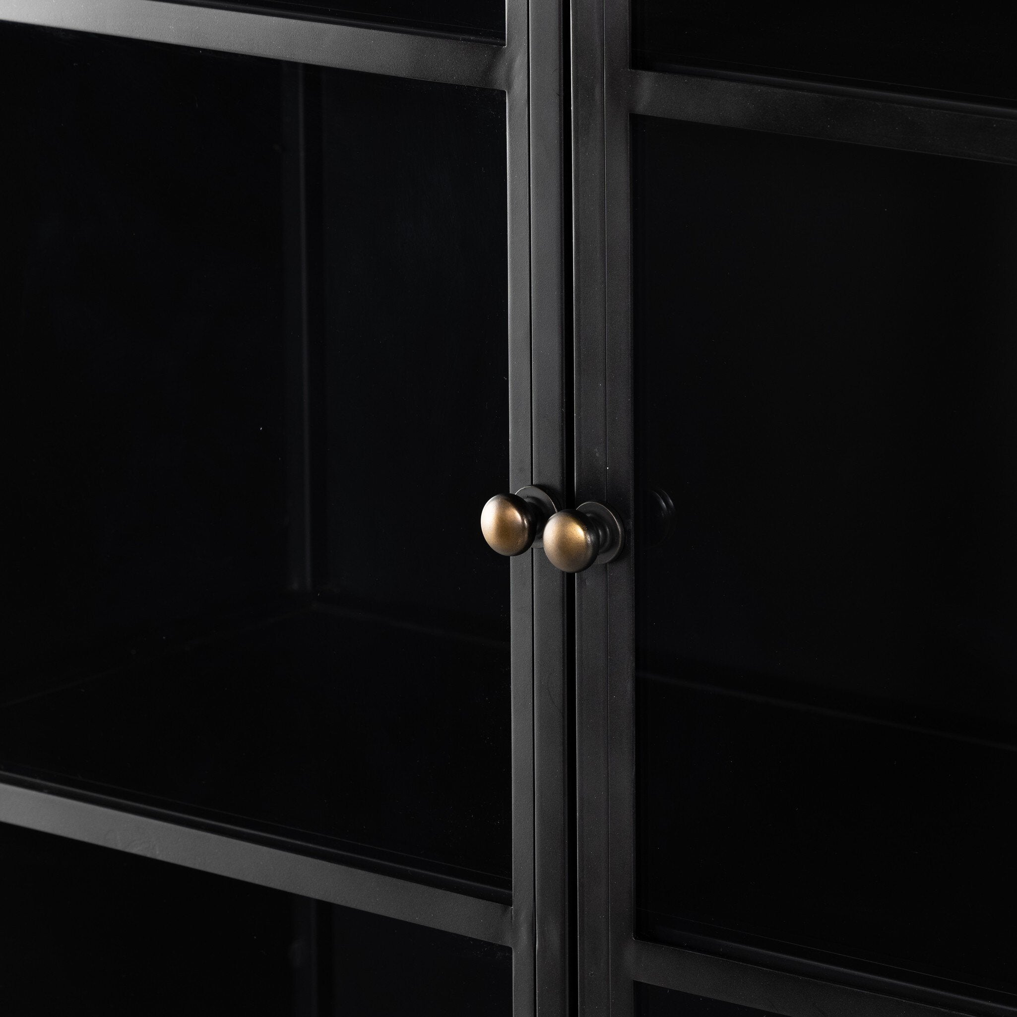 Black metal cabinet with gold knobs on a black background