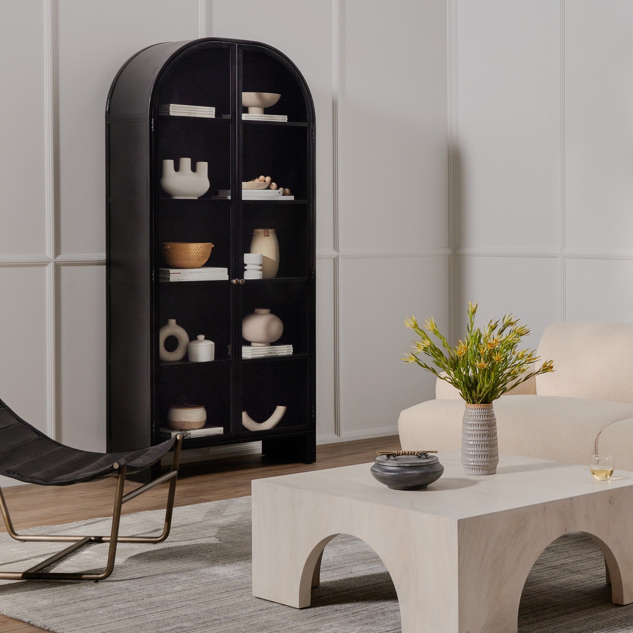 Modern living room with a black curved bookshelf, beige sofa, and decorative items.