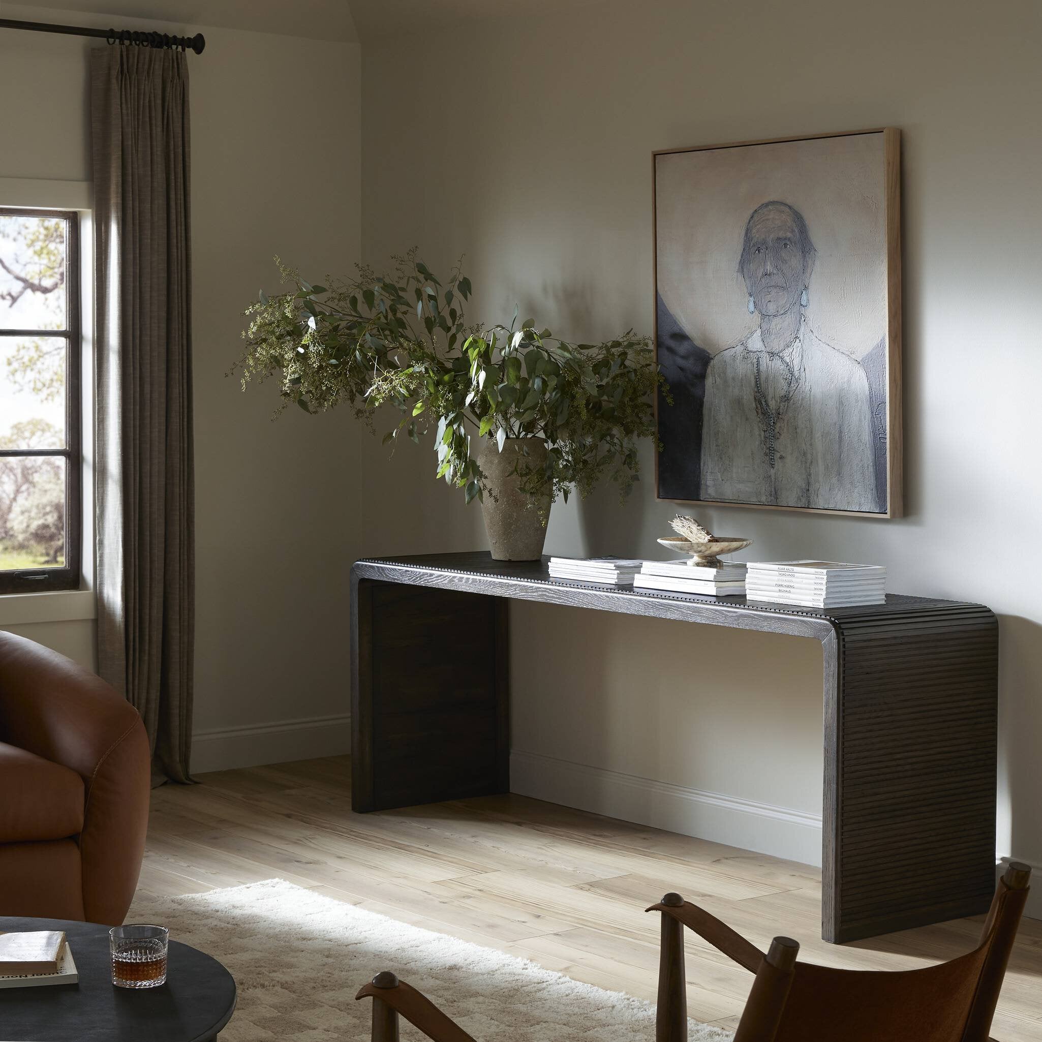 Modern living room with a console table, chairs, and a painting on the wall.