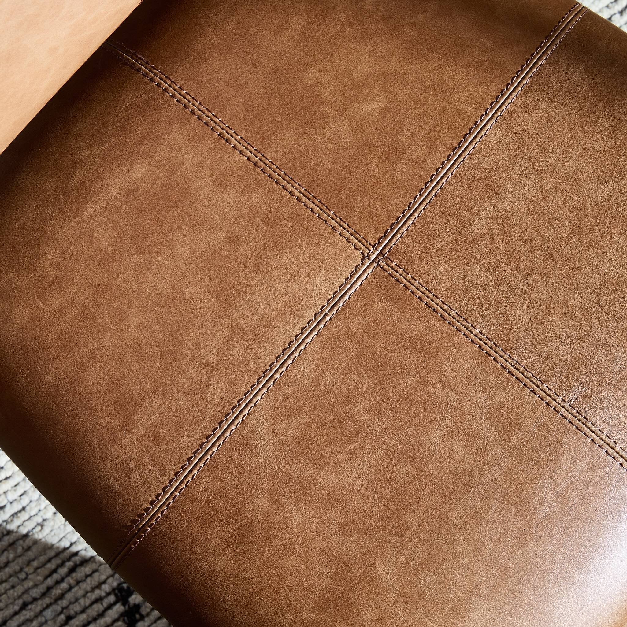 Close up of a brown leather dining chair with wooden frame on a white background.